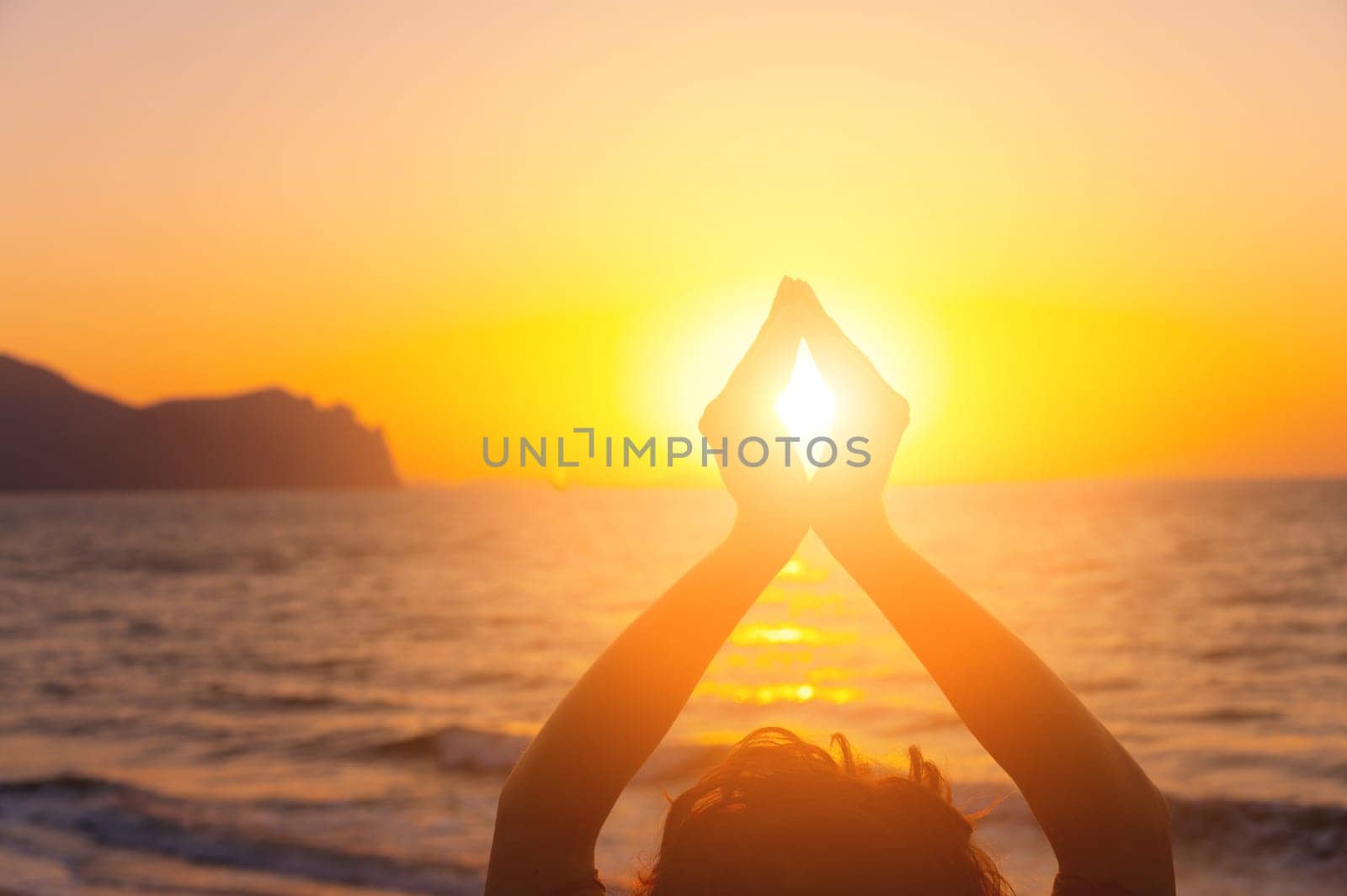 young woman raises her hands, praying in the light of sunset or sunrise. silhouette of female hands during sunset.