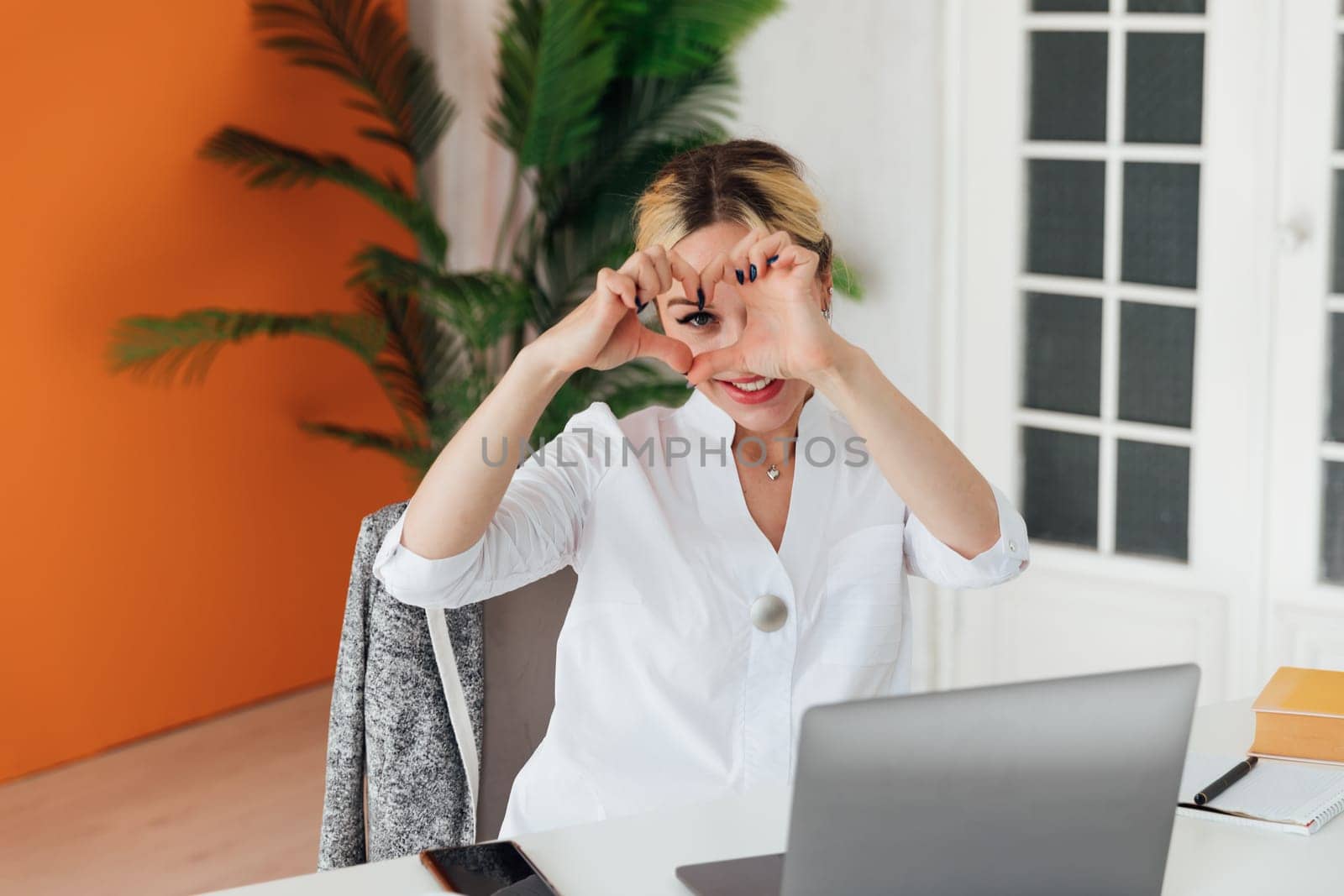 Beautiful woman showing her hands heart in office