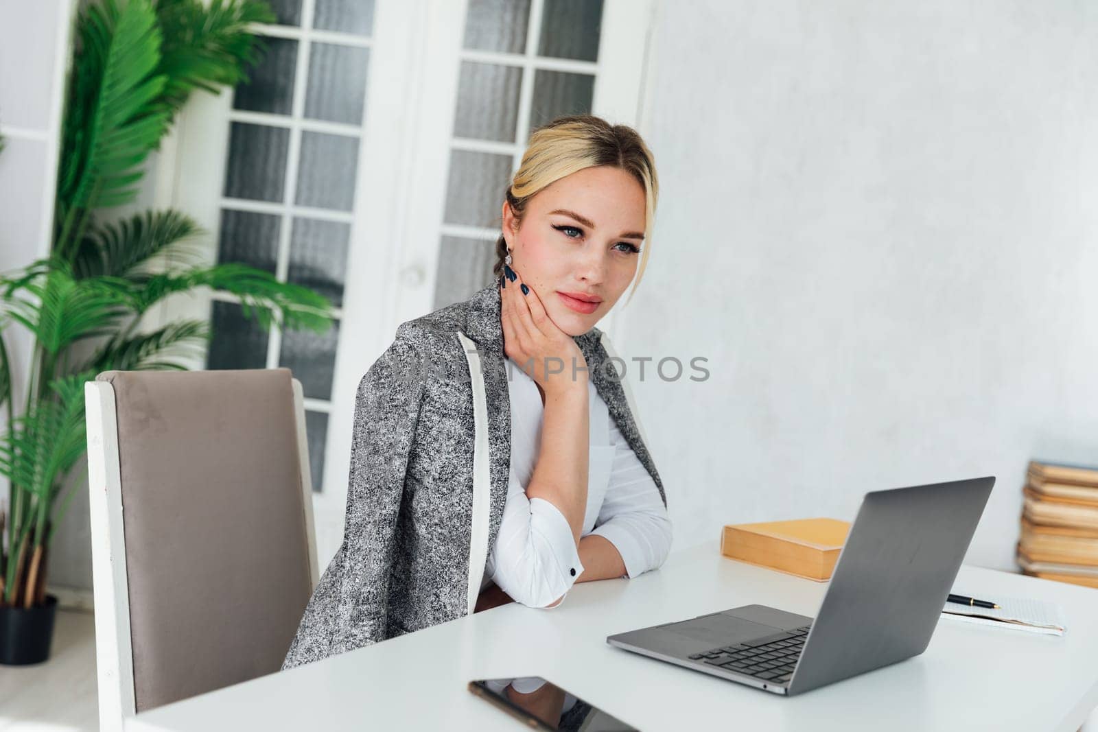 Image of young pleased happy cheerful cute beautiful business woman sit indoors in office using laptop computer listening music with earphones.