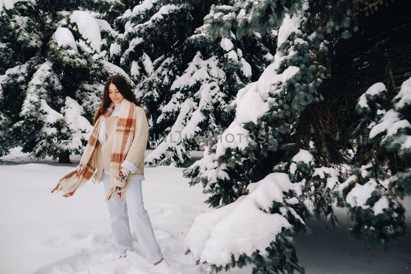 Portrait of a girl with long hair in mittens in a winter forest . Snowy winter.