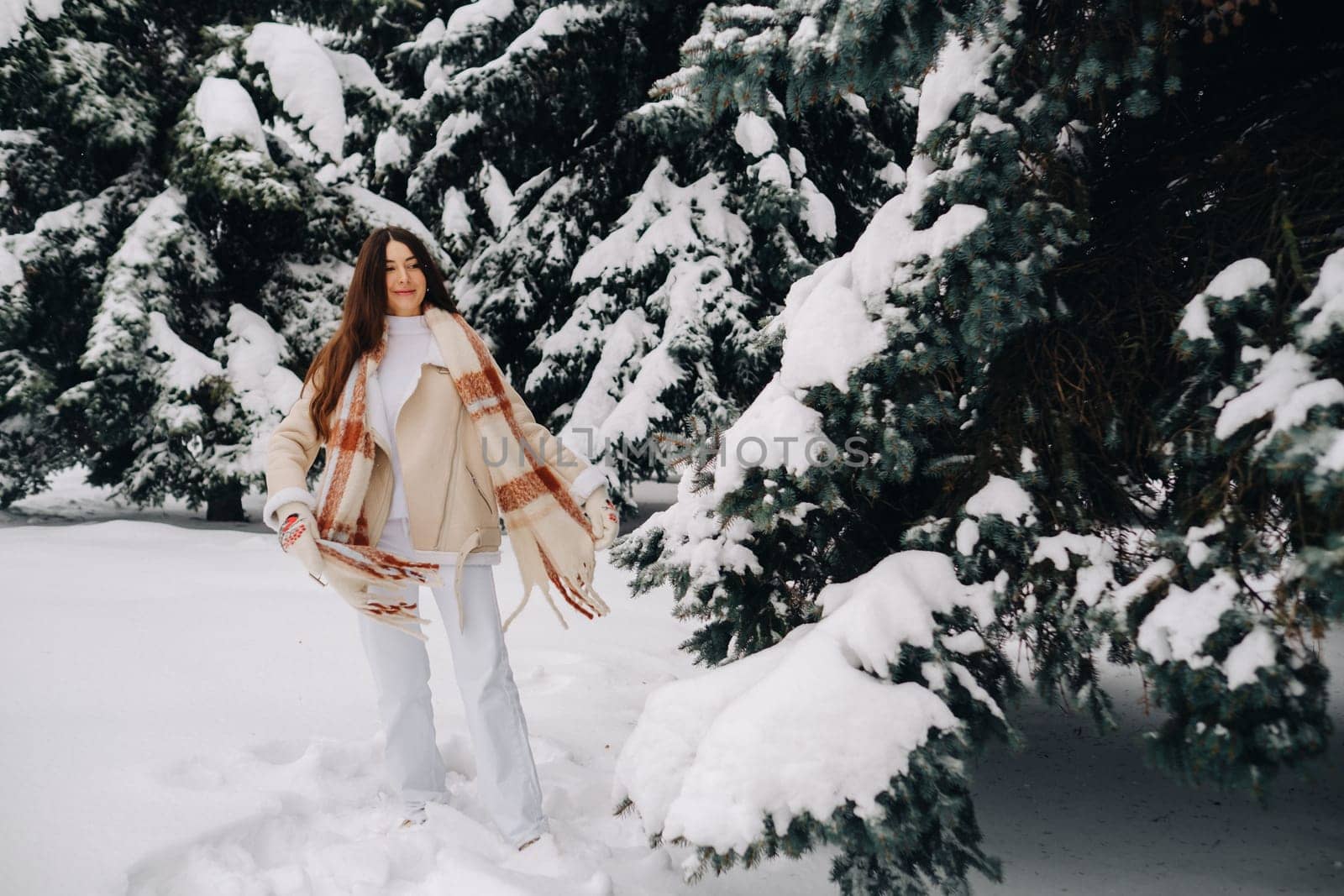 Portrait of a girl with long hair in mittens in a winter forest . Snowy winter.