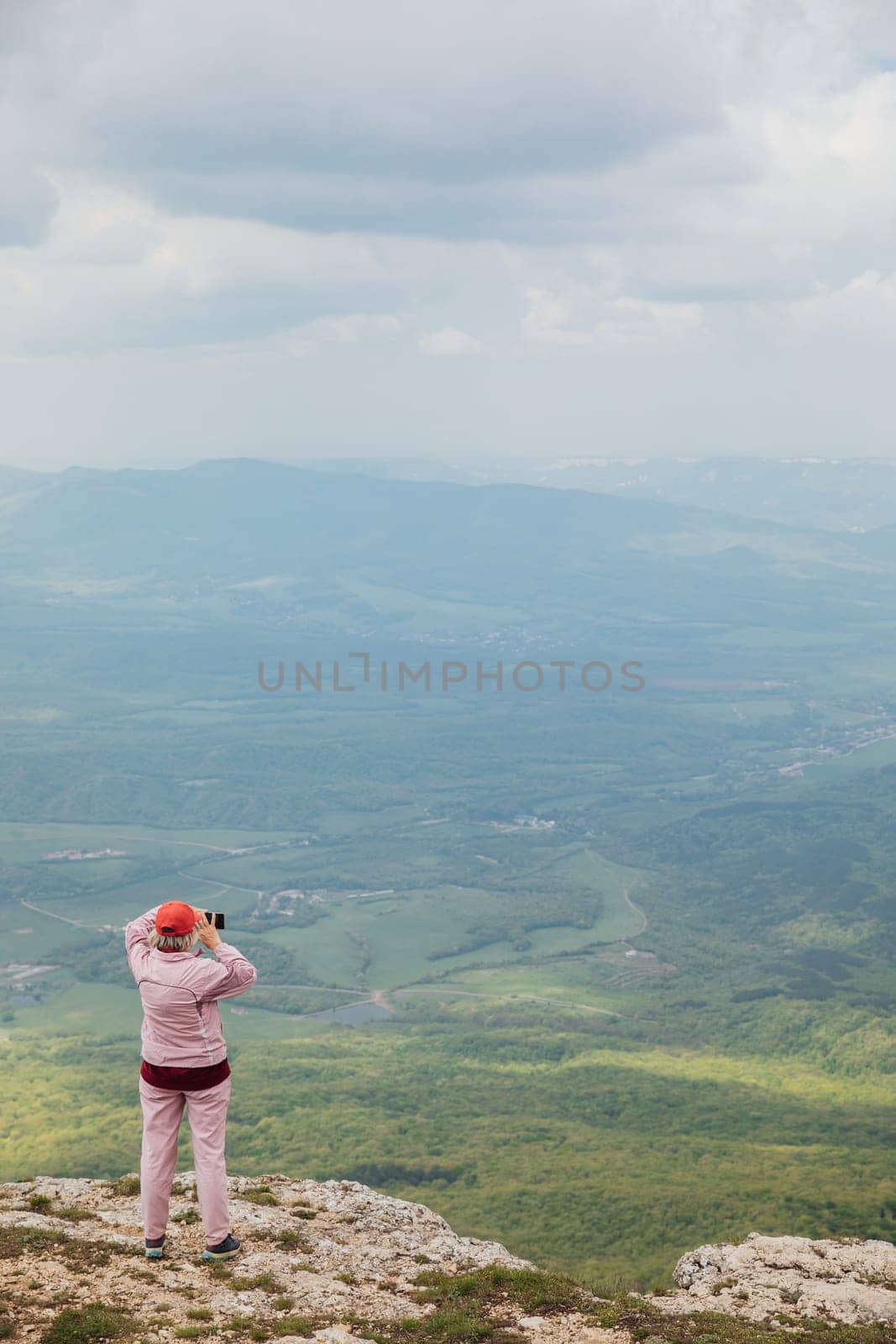 tourist taking pictures of the landscape from the top of the mountain while hiking