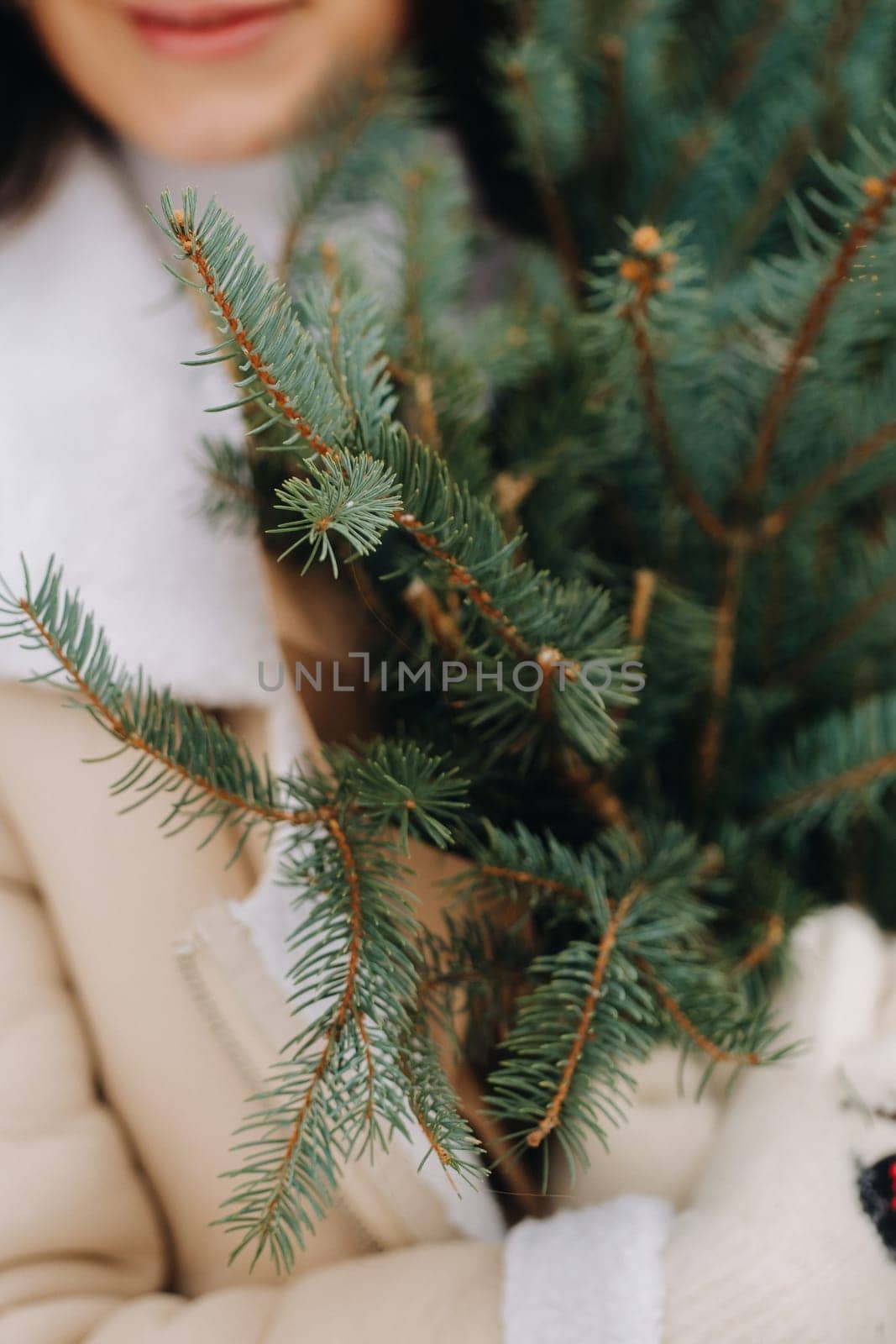 A girl with long hair in winter on the street with a bouquet of fresh fir branches.