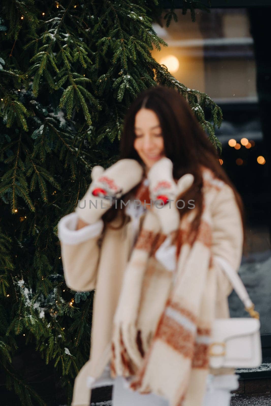 A girl with long hair in a scarf and with a white handbag walks down the street in winter by Lobachad