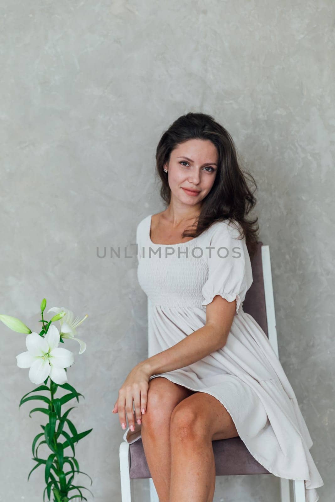Beautiful brunette woman in white summer dress with beautiful flower by Simakov