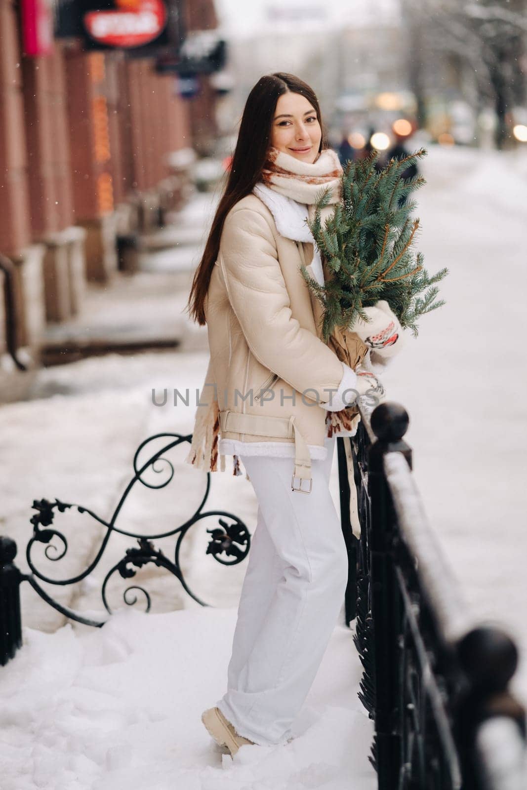 Girl with long hair in winter on the street with a bouquet of fresh spruce branches by Lobachad