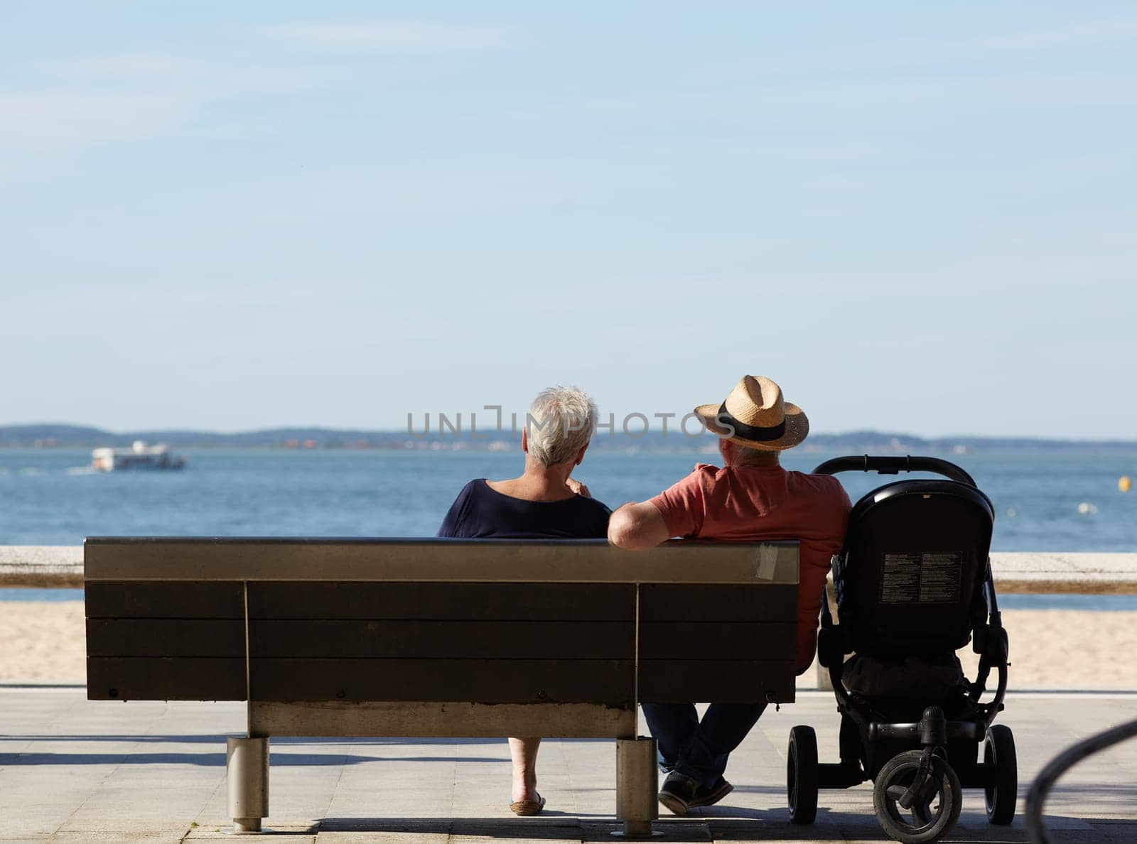 couple sitting on a bench looking at the sea by lhorintson