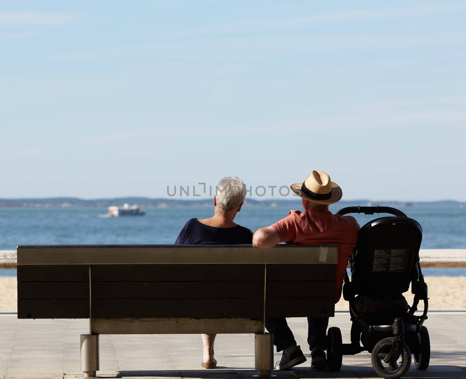 couple sitting on a bench looking at the sea by lhorintson