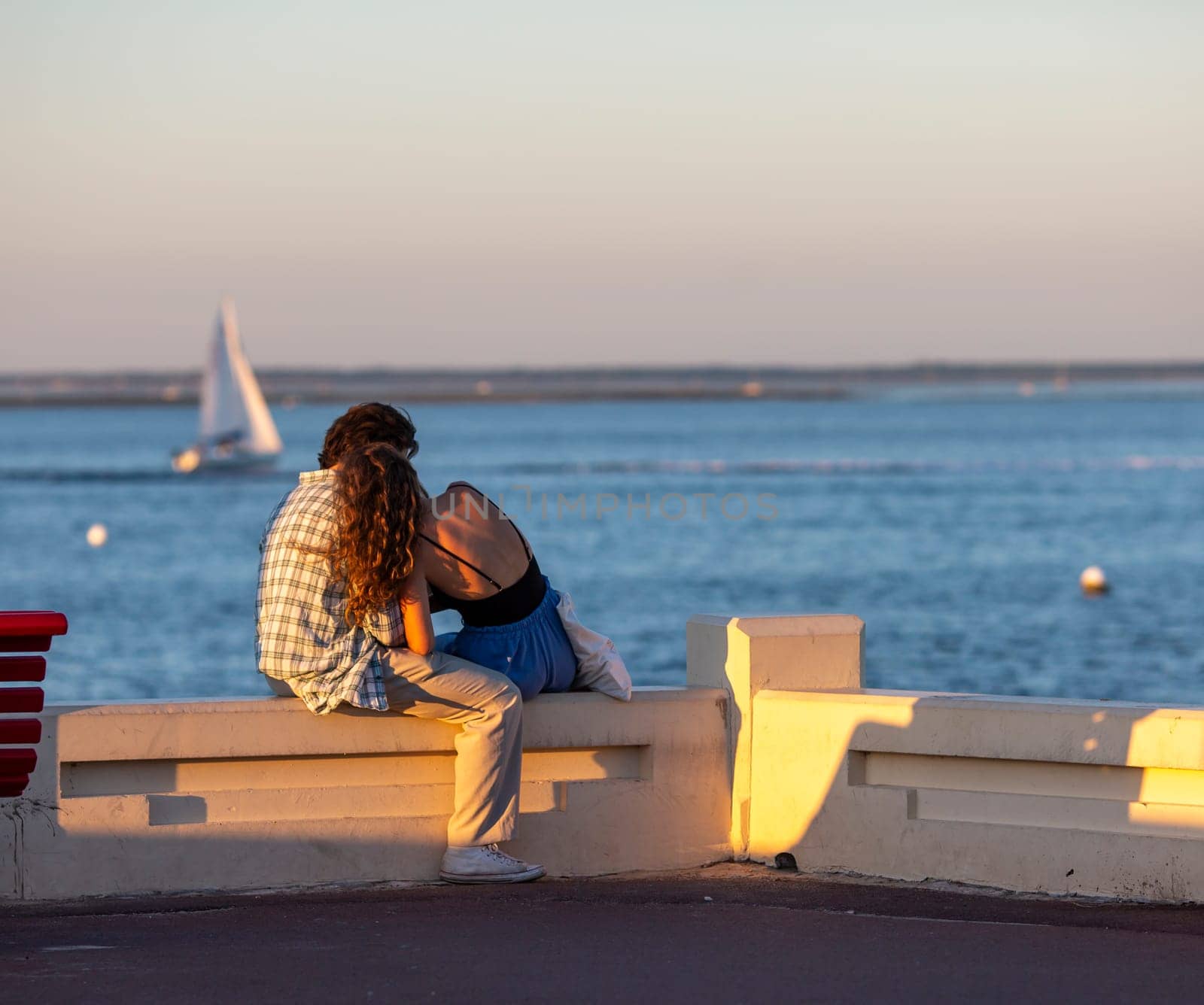 couple sitting on a bench looking at the sea by lhorintson