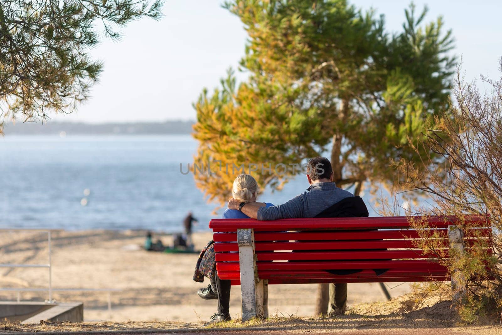 couple sitting on a bench looking at the sea by lhorintson