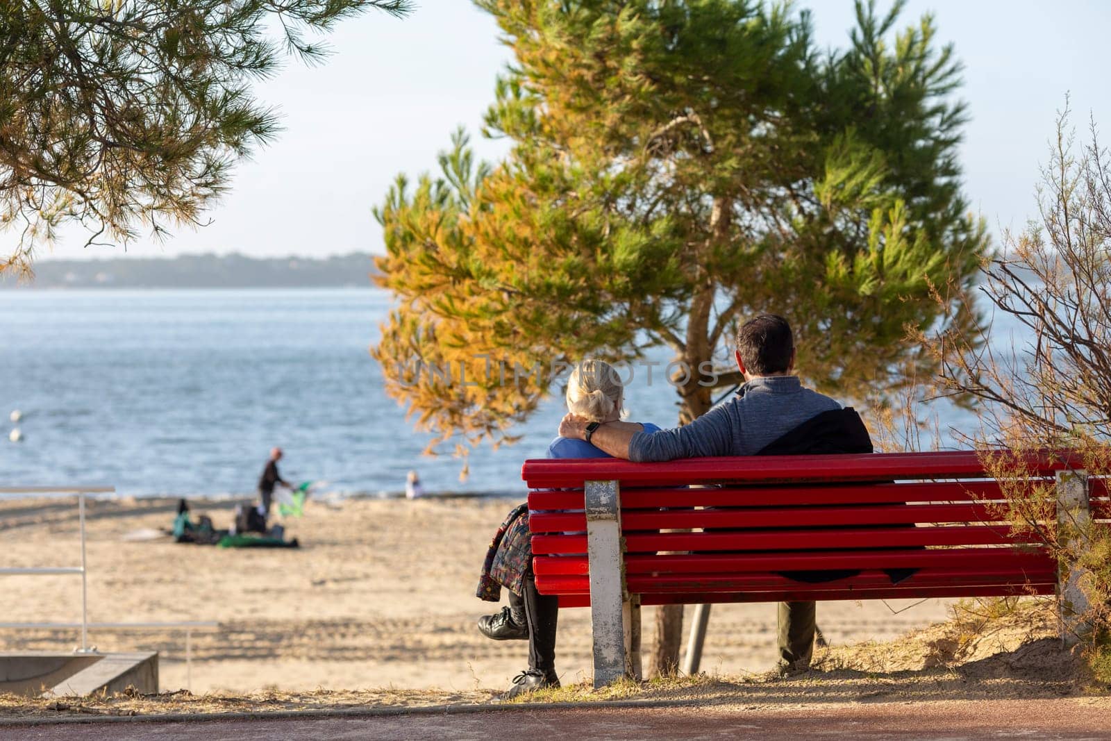 couple sitting on a bench looking at the sea by lhorintson