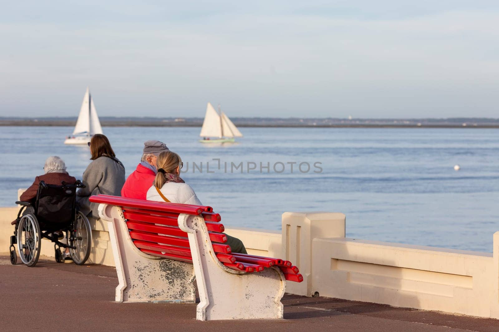 couple sitting on a bench looking at the sea by lhorintson