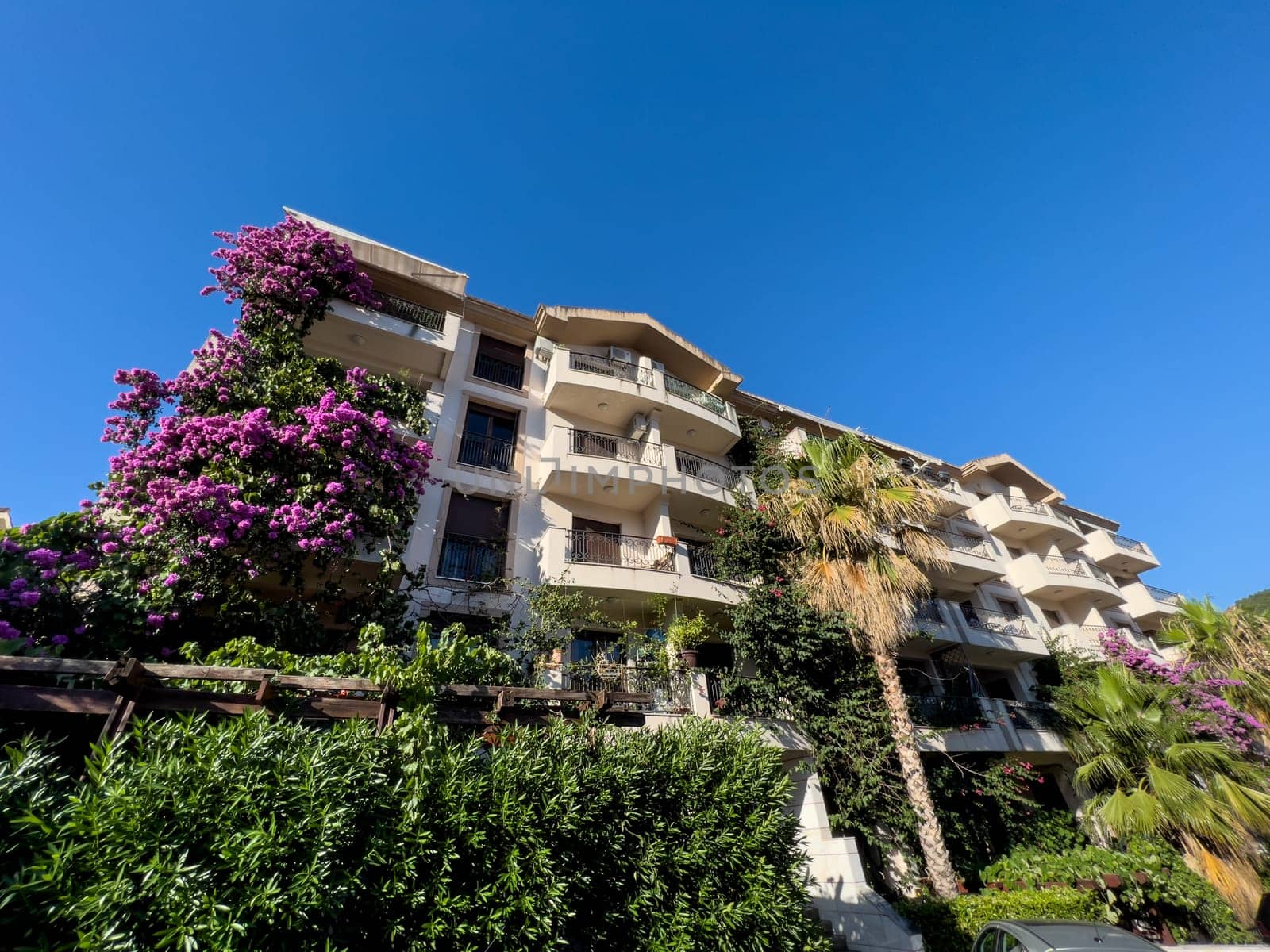 Multi-storey hotel with terraces and a green garden with blooming lilacs. High quality photo