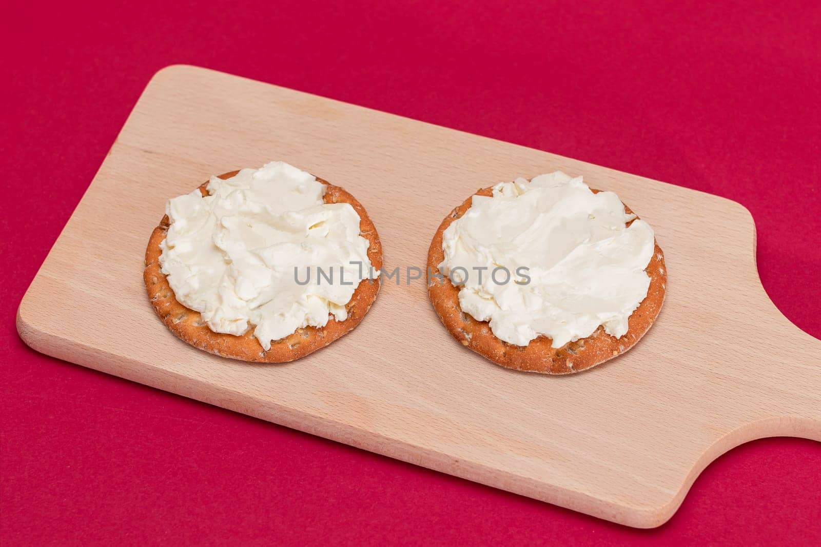 Crispy Cracker Sandwich with Cream Cheese on Wooden Cooking Board on Magenta Background