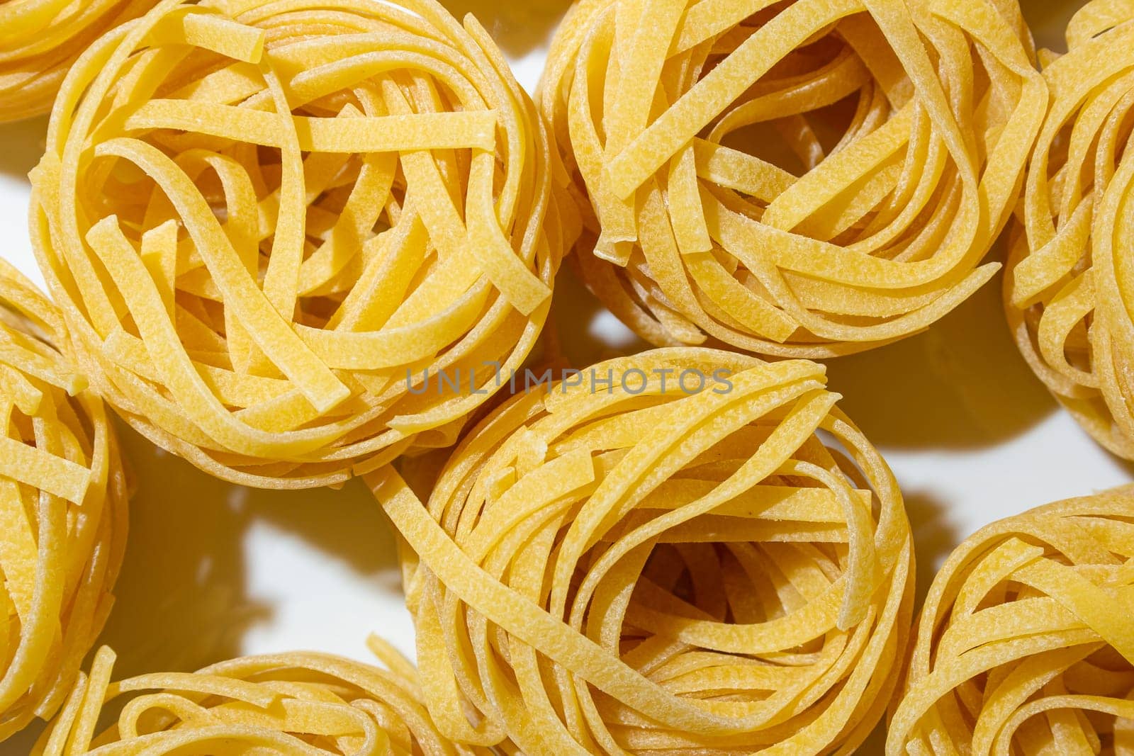 Uncooked Egg-Based Fettuccine Pasta: A Culinary Canvas of Ribbon-Shaped Macaroni, Creating a Lively and Textured Background for Gourmet Cooking. Dry Pasta. Raw Macaroni - Top View, Flat Lay