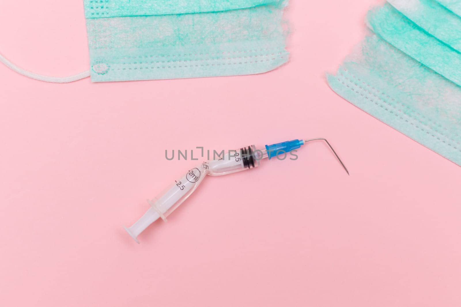 Anti Vaccine Movement and Anti Mask Concept - Broken Medical Syringe and Green Torn Medical Face Mask on the Pink Background. Pandemic and Lockdown End - Top View, Flat Lay