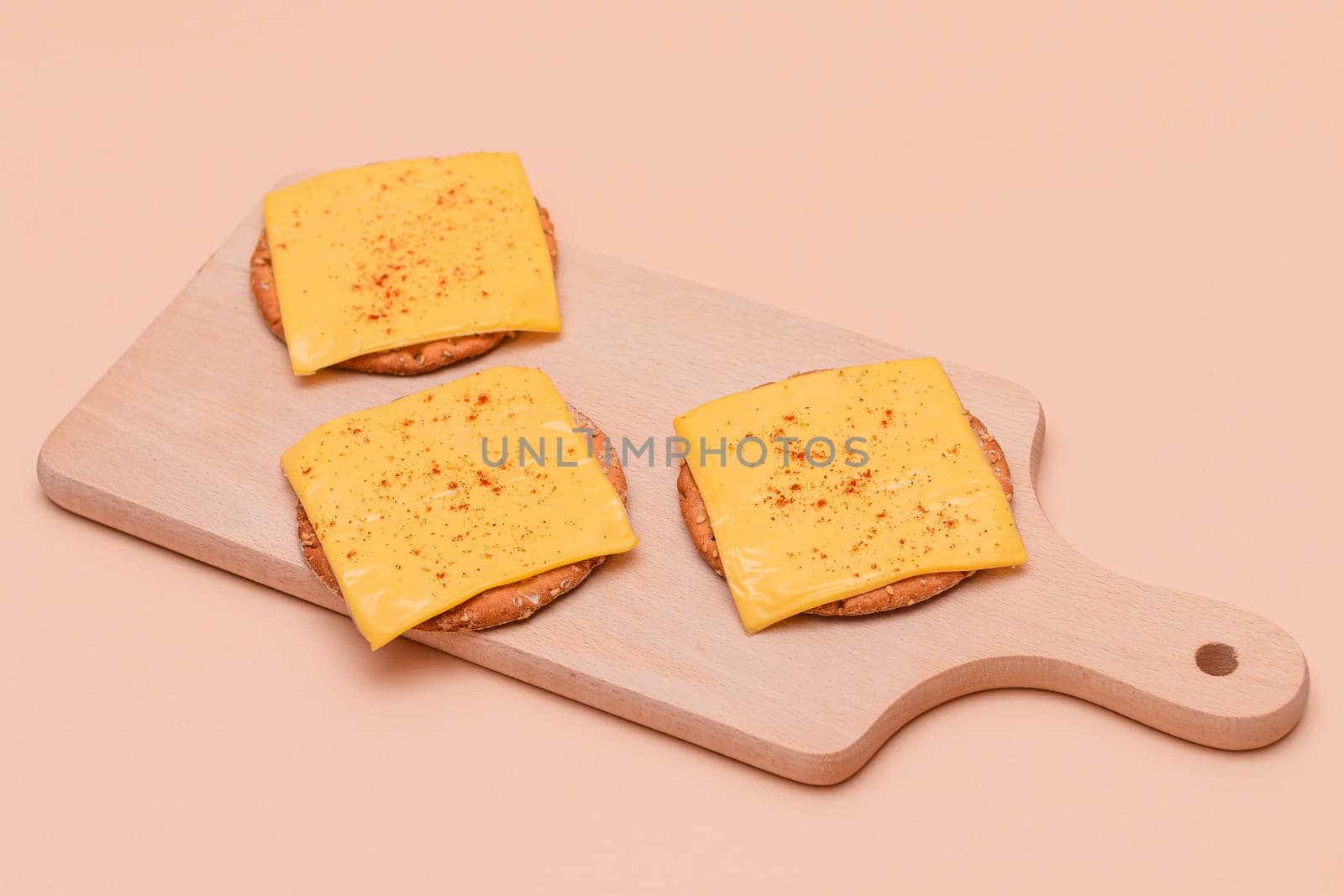 Cracker Sandwiches with Cheese and Paprika on Cutting Board by InfinitumProdux