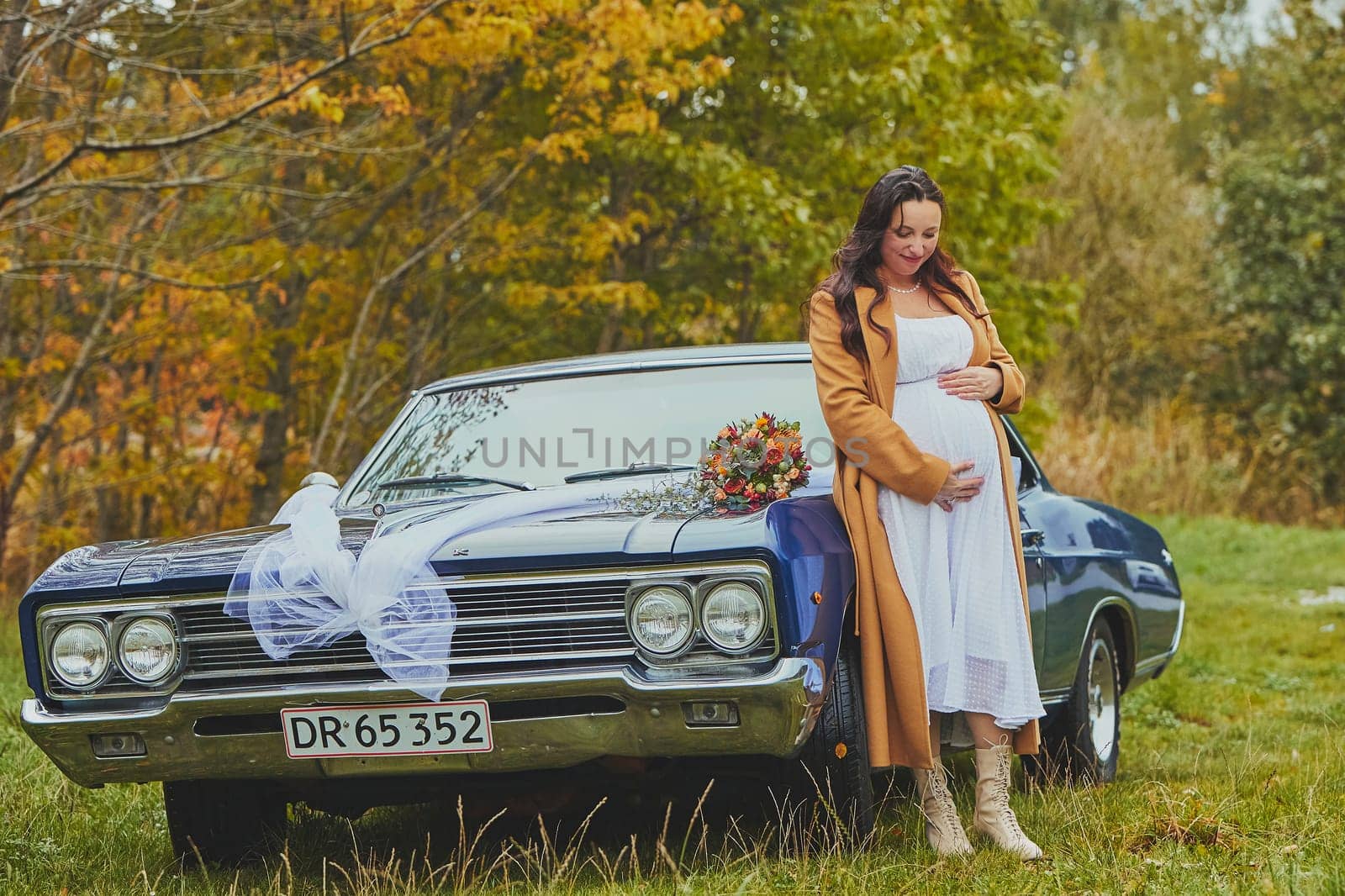 Vejle, Denmark, October 26, 2023: Pregnant woman near a retro car by Viktor_Osypenko