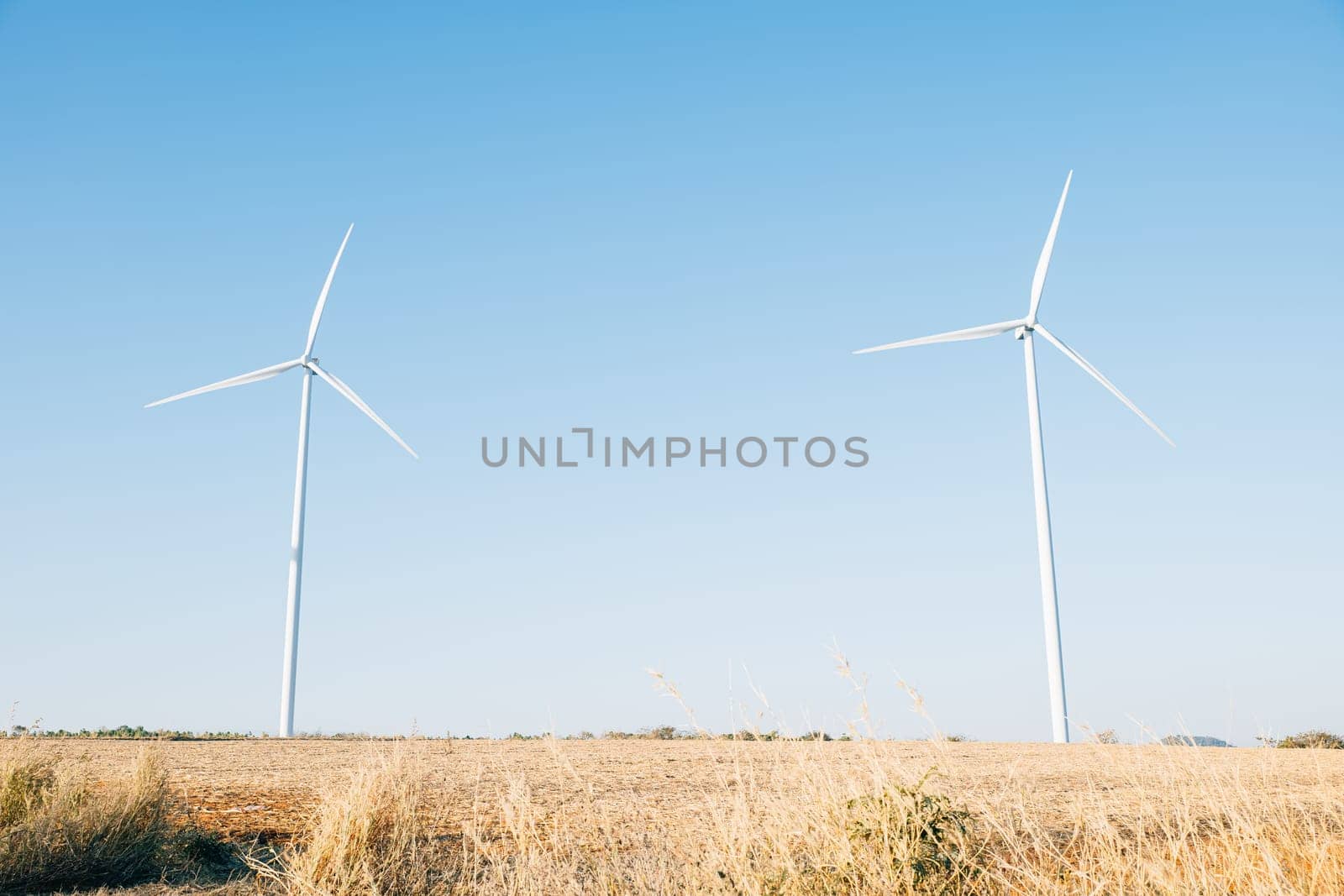 A windmill farm on a mountain captures nature's wind generating clean energy. Innovative turbines against a blue sky symbolize sustainable development.