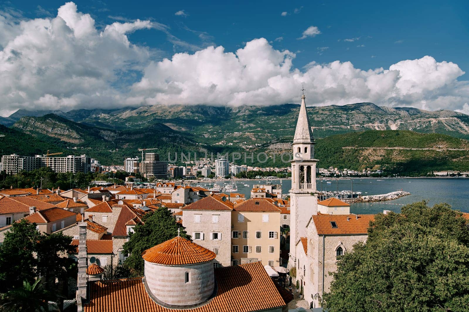 Church of the Holy Trinity near St. John Cathedral among old houses with red roofs. Budva, Montenegro by Nadtochiy