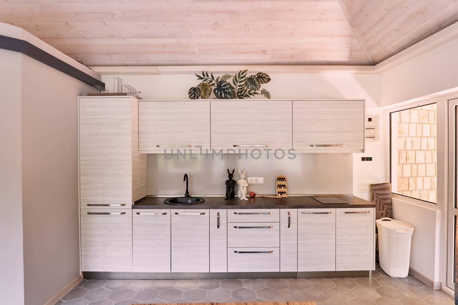 White wooden cabinets with black sink and faucet in the kitchen. High quality photo