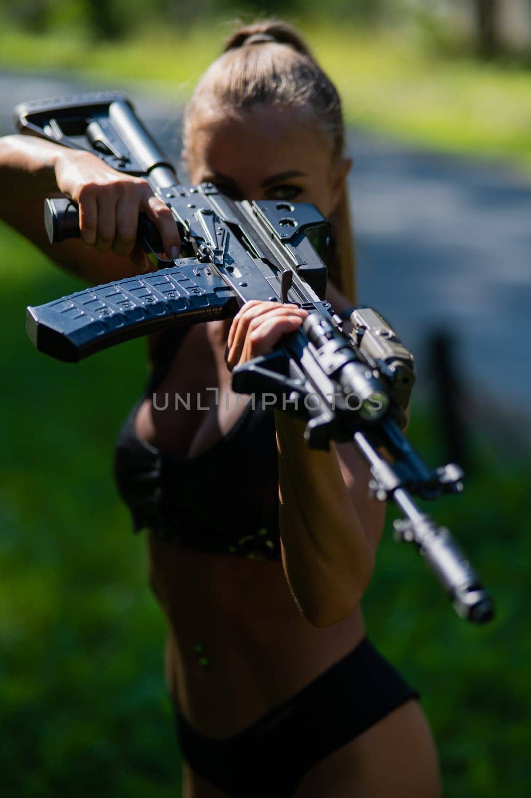 Caucasian woman in bikini with machine gun outdoors