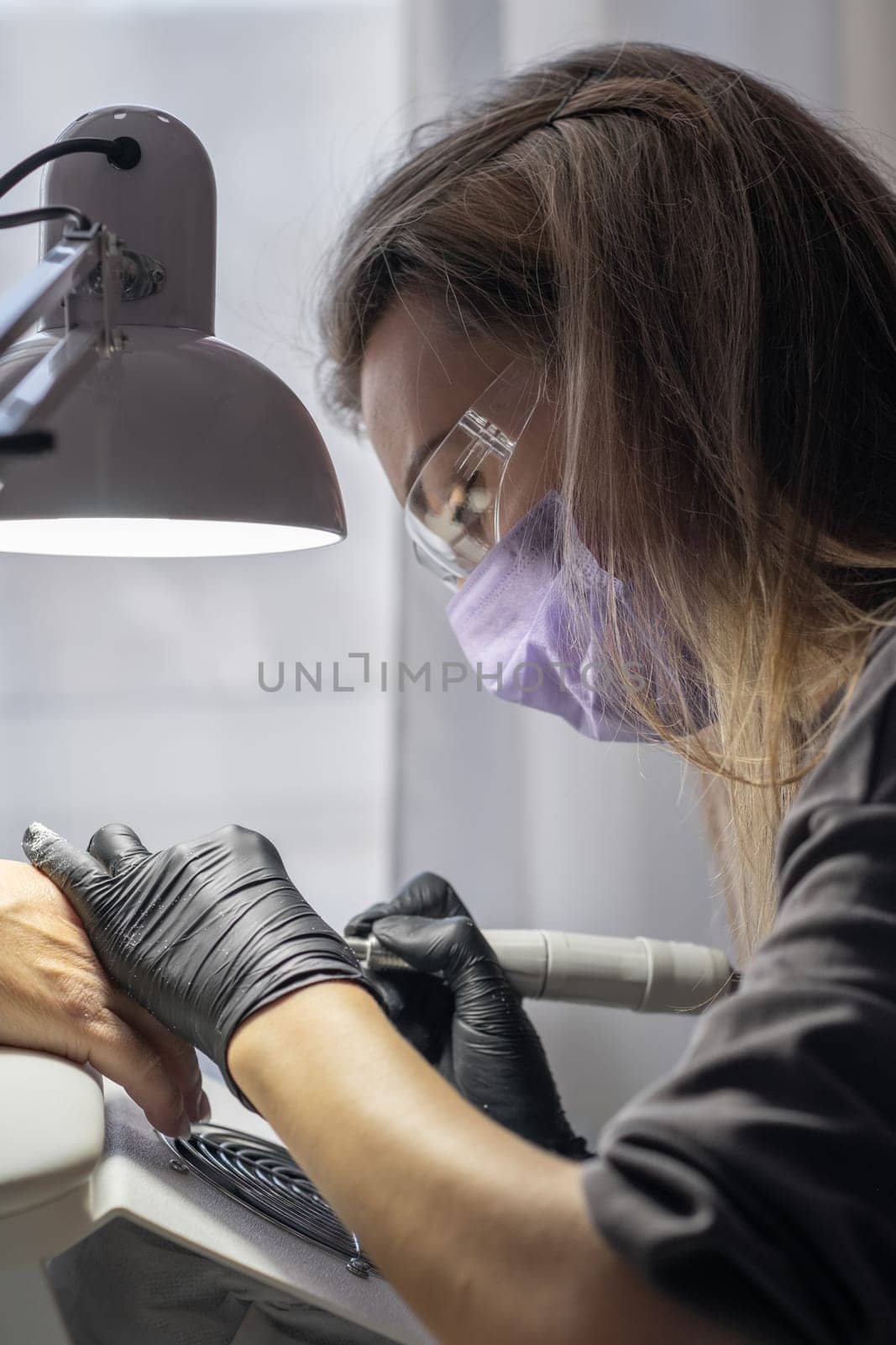Manicurist at work. Professional manicurist removes worn nail design by AnatoliiFoto