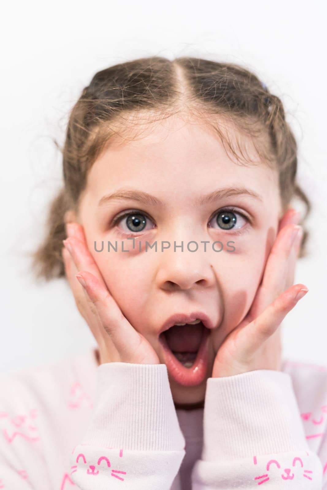 Little girl with rainbow braces with a surprised face.