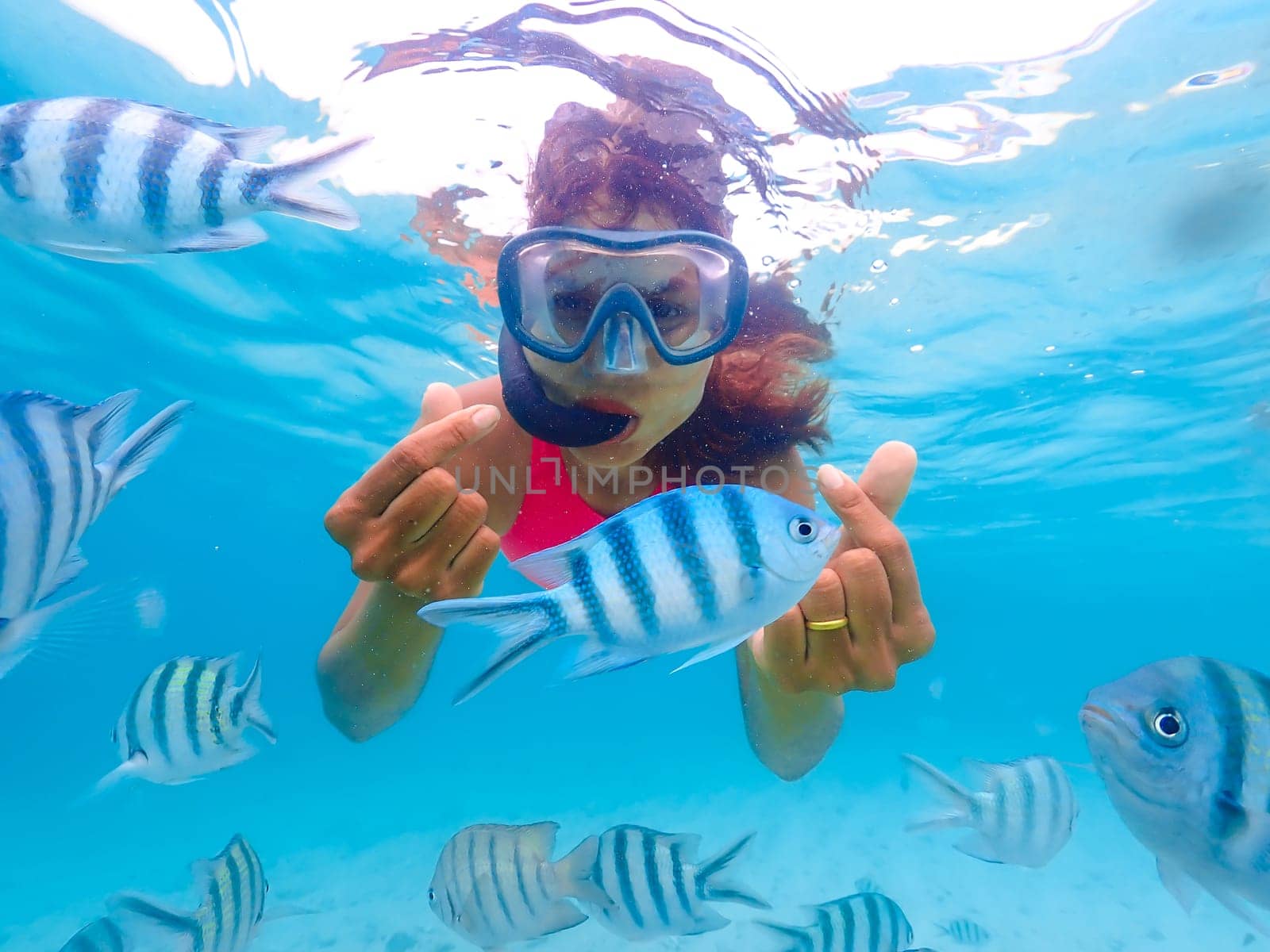 Asian woman on a snorkeling trip at Samaesan Thailand. dive underwater with Nemo fishes in the coral reef sea pool. swim activity on a summer beach holiday
