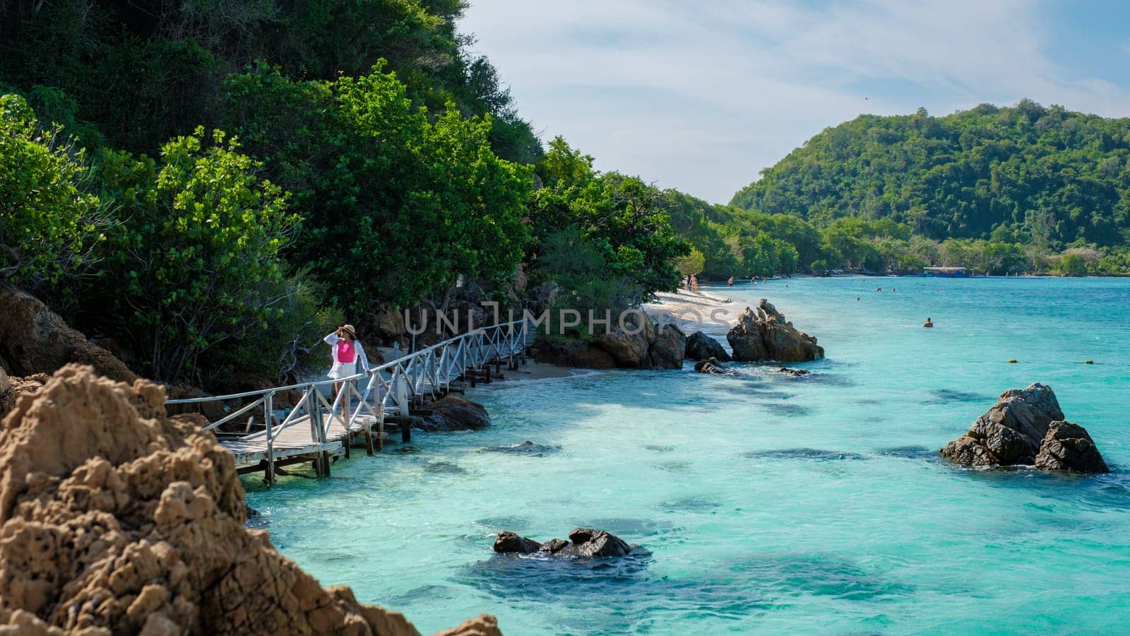 Asian woman on a day trip to Ko Kham Island Sattahip Chonburi Samaesan Thailand a tropical Island in Thailand with a blue ocean, woman at the beach of a tropical island standing at a wooden jetty