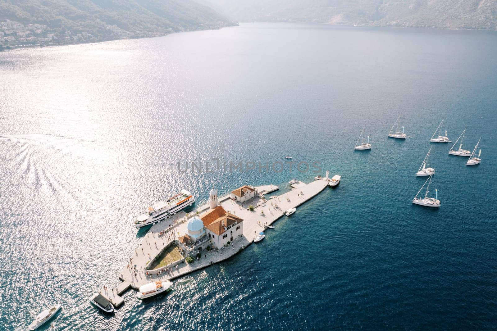 Motor boats and sailboats are moored around the island of Gospa od Skrpjela. Montenegro. Drone. High quality photo