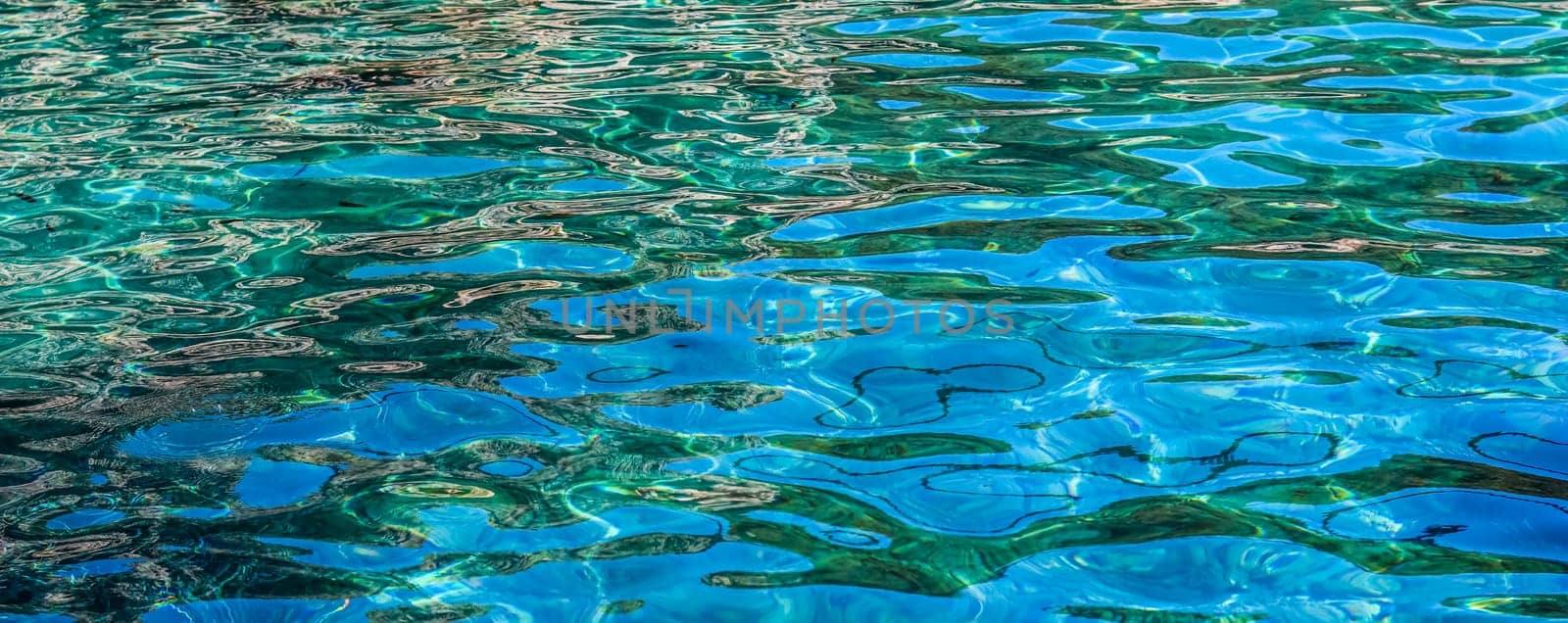 Emerald sea water in sunshine glow as surface background. Summer holidays concept