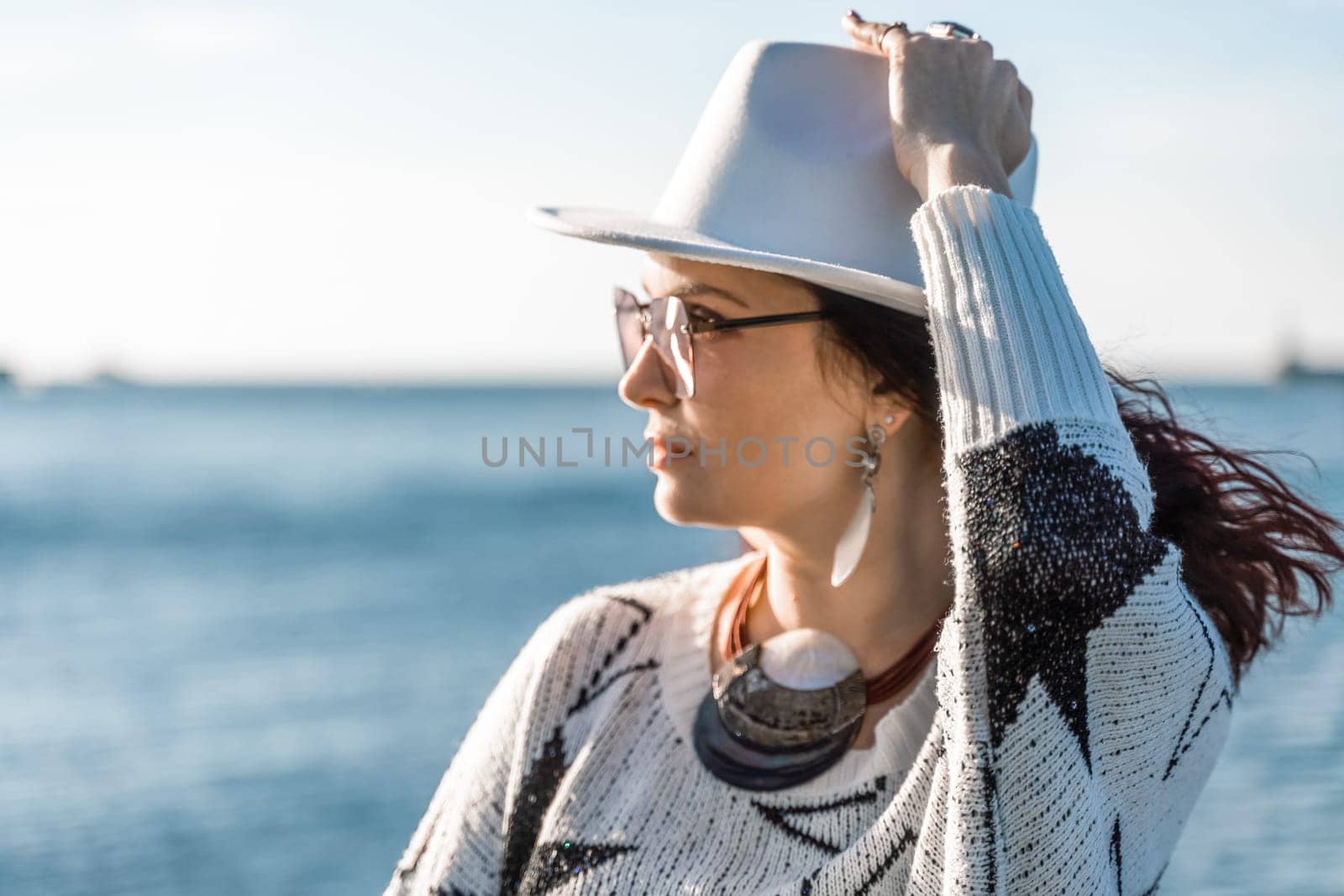 Portrait of a curly haired woman in a white hat and glasses on t by Matiunina