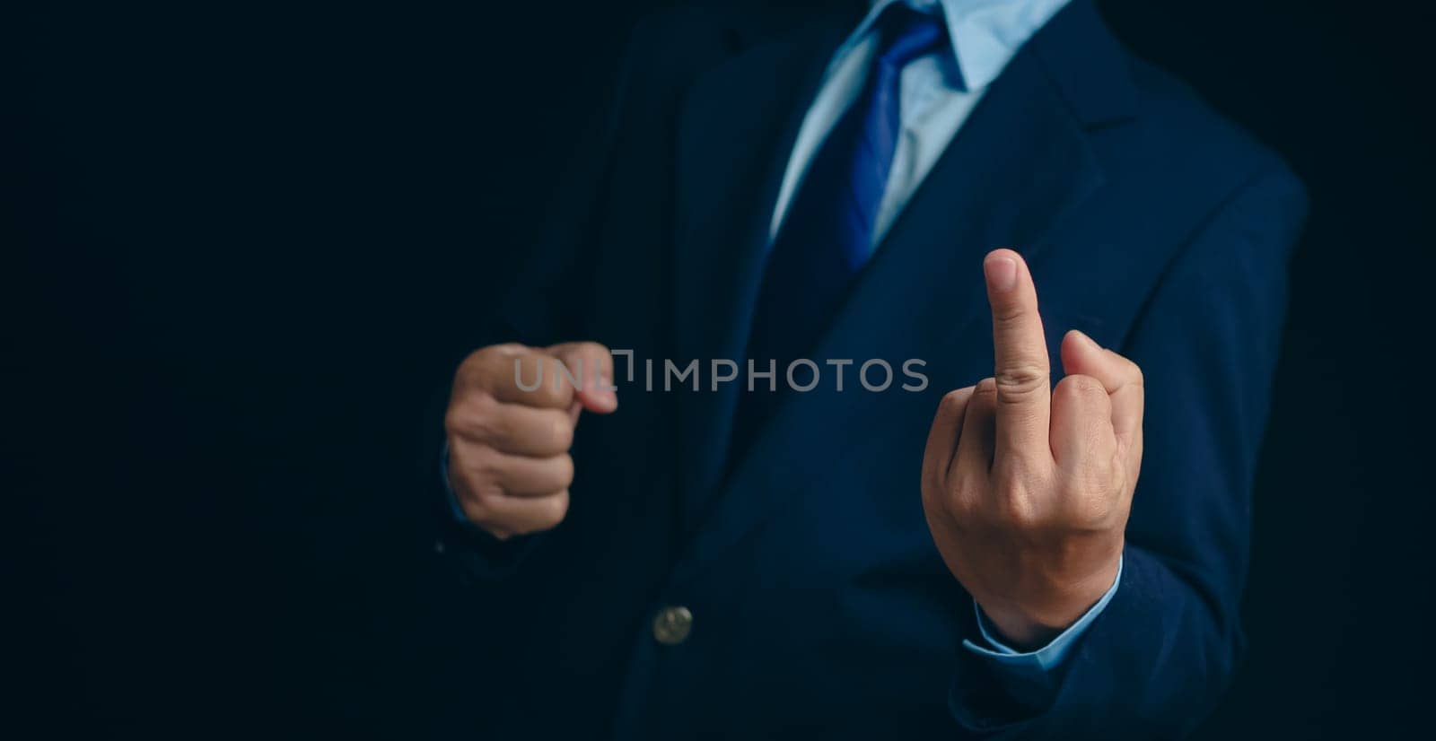 Angry, stress and portrait of businessman with a middle finger on a dark background in studio. Crazy, anger and a frustrated Japanese businessman showing an offensive, vulgar and rude hand gesture by Unimages2527