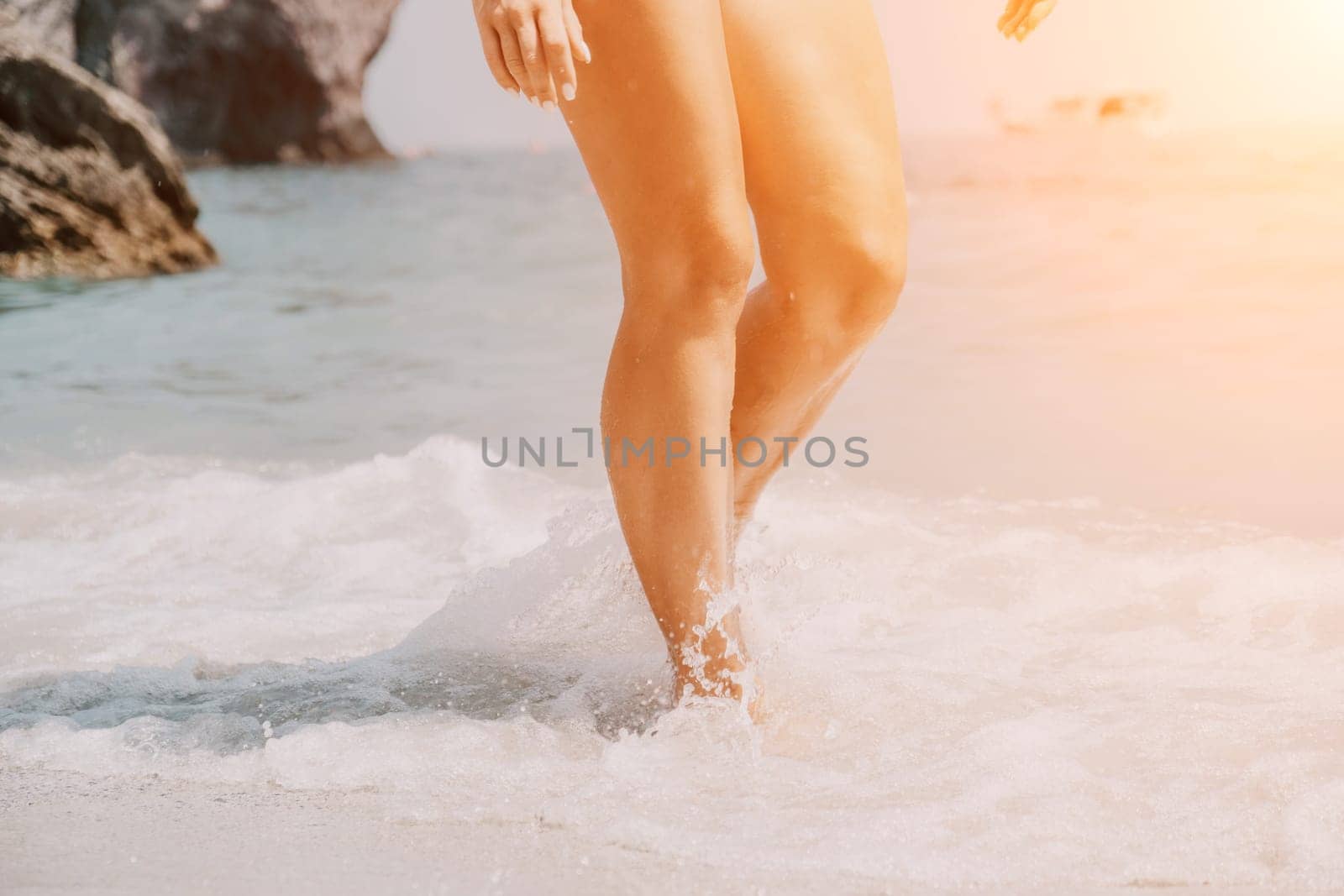 Sea beach travel - woman walking on sand beach leaving footprints in the white sand. Female legs walking along the seaside barefoot, close-up of the tanned legs of a girl coming out of the water. by panophotograph