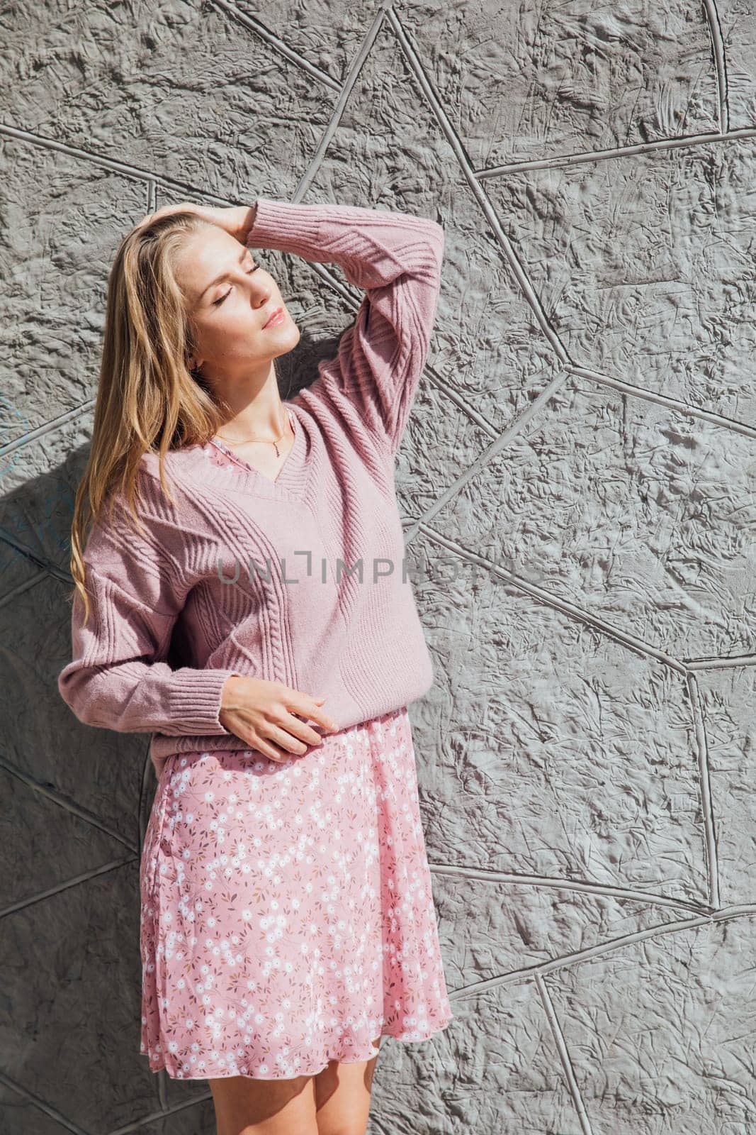 Beautiful slender blonde woman in pink clothes on a walk outdoors by Simakov