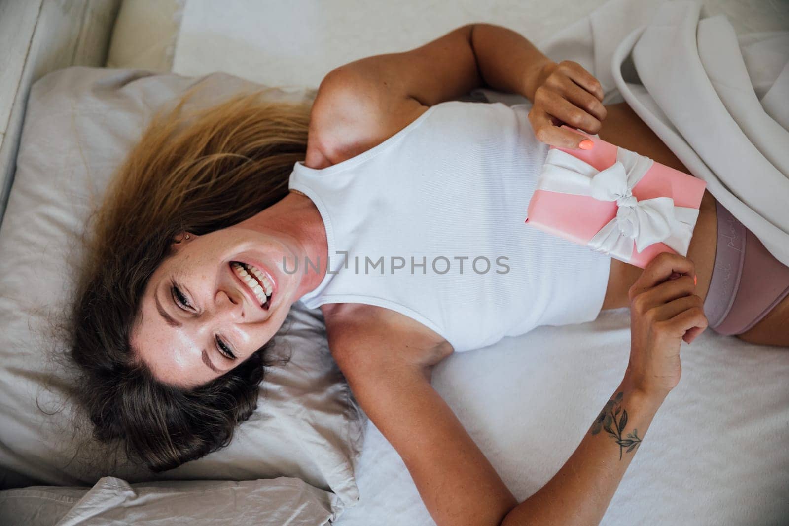 Beautiful young woman in bedroom on bed received holiday gift