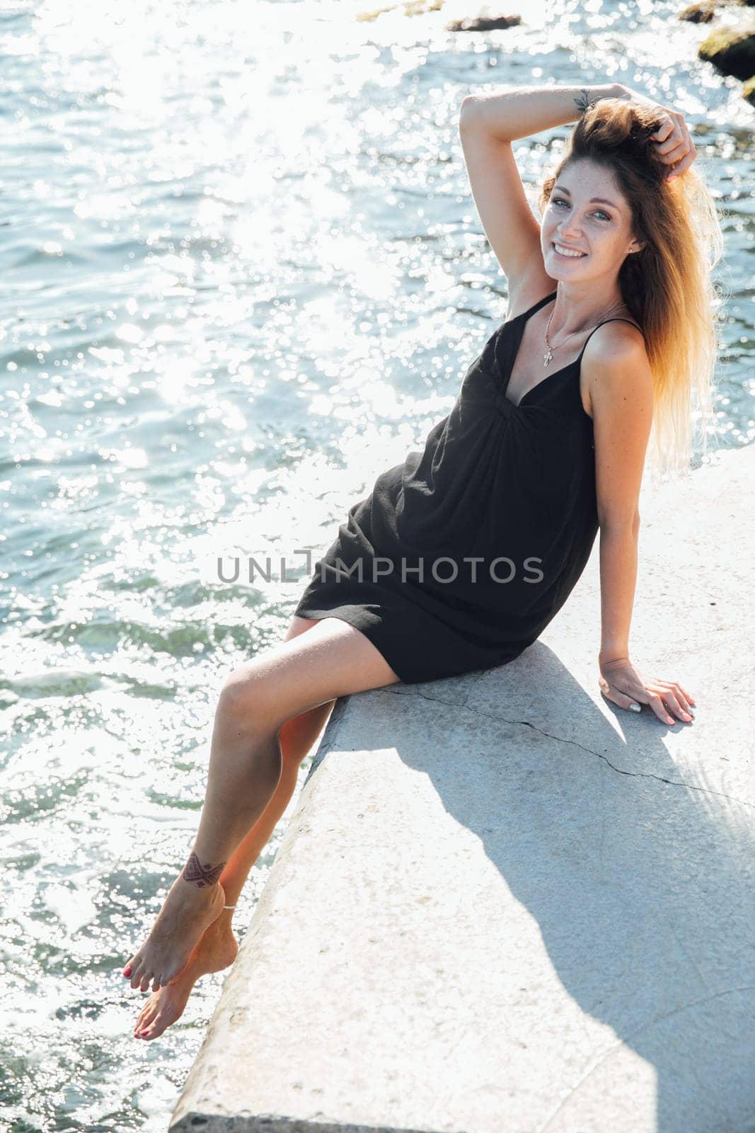 Beautiful slender fashionable woman in black summer dress walking on the streets of the city by Simakov