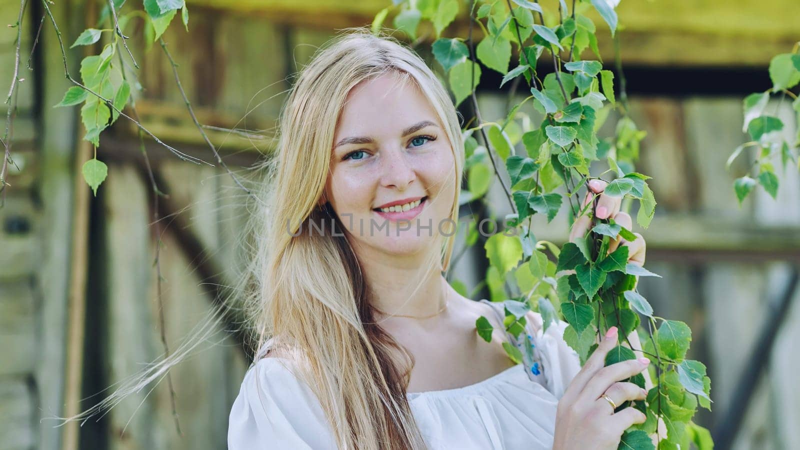 Russian girl posing by the branches of a birch tree