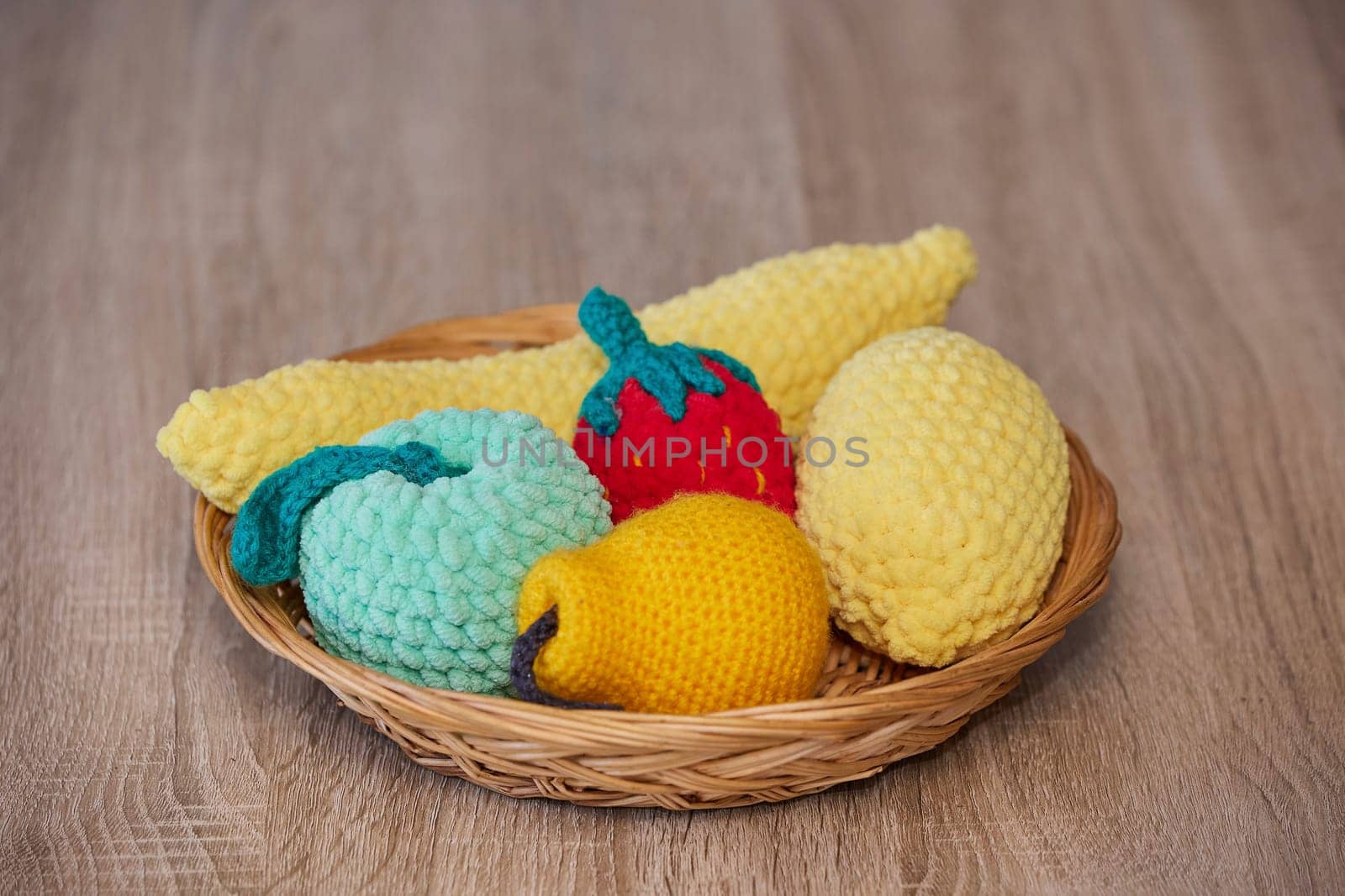 Cute knitted fruits toys on a wicker plate.