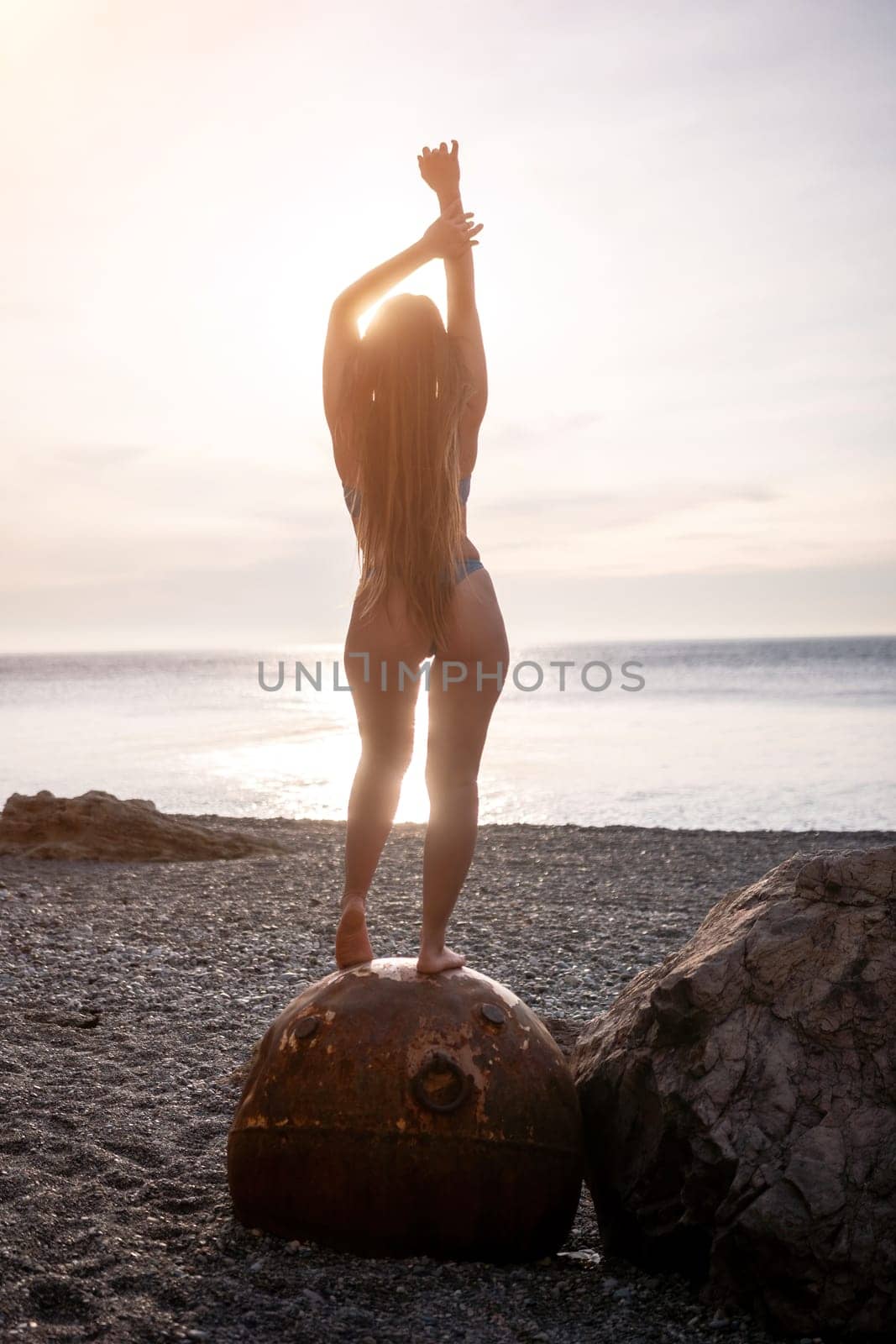 Woman summer travel sea. A happy tourist enjoys taking pictures of her travels, posing by an old, rusty sea mine on a beach surrounded by volcanic mountains, sharing travel adventure journey by panophotograph
