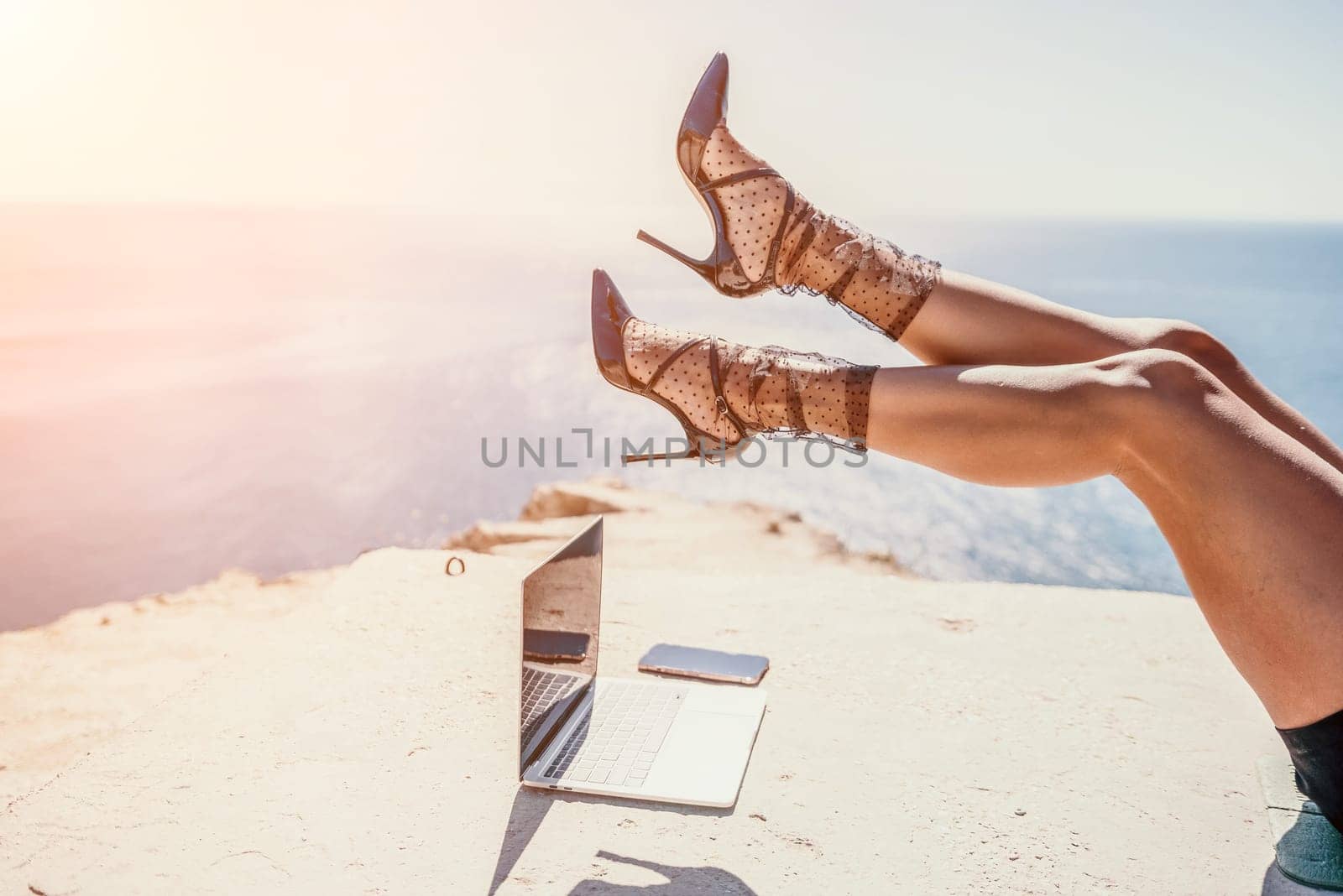 Happy girl doing yoga with laptop working at the beach. beautiful and calm business woman sitting with a laptop in a summer cafe in the lotus position meditating and relaxing. freelance girl remote work beach paradise