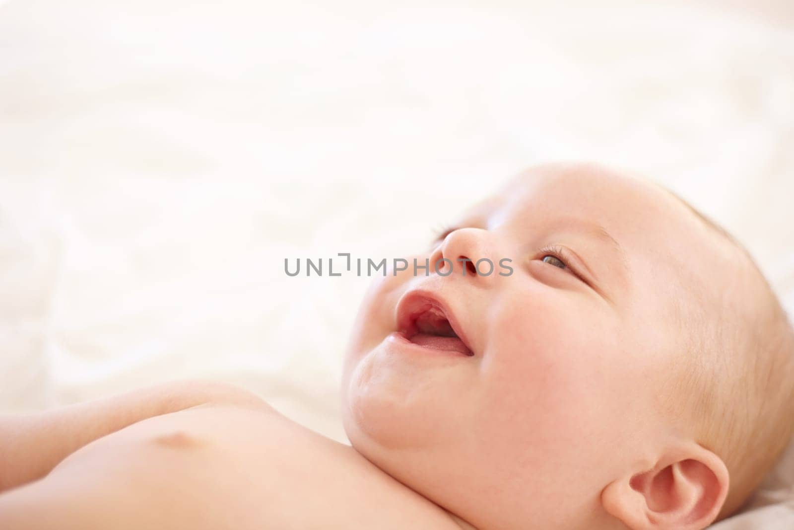 Baby, smile on bed and funny laugh of young child in development, innocent and relax at home. Happy kid, excited infant in nursery and rest in bedroom, healthy body and cute, adorable or mockup space.
