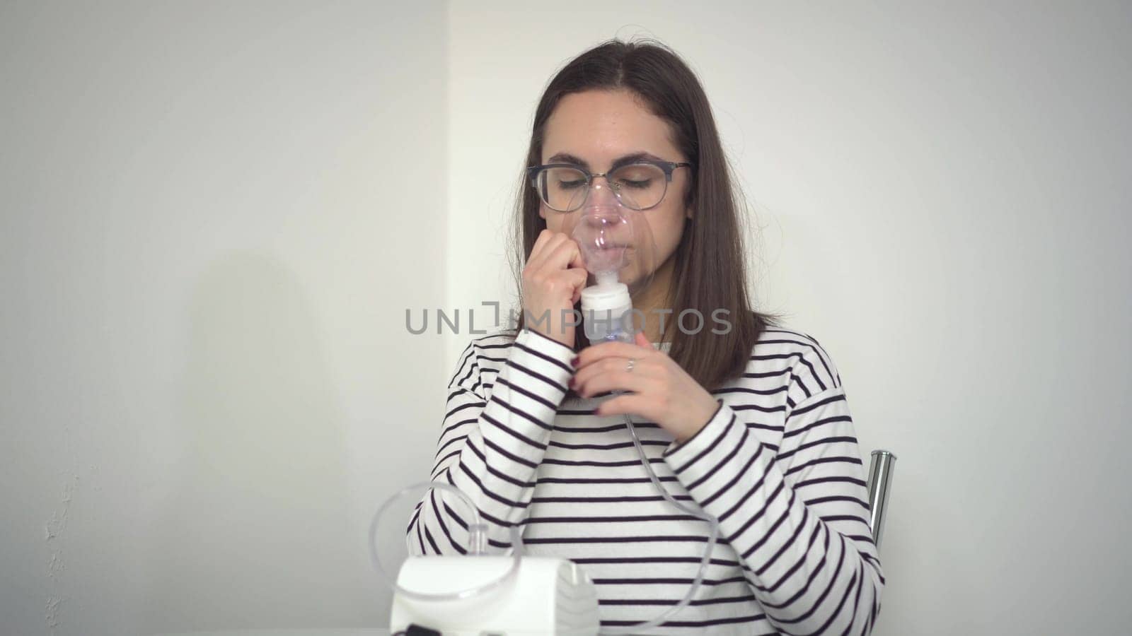 A young woman breathes through an inhaler mask. A girl in glasses with an oxygen mask is being treated for a respiratory infection. 4k