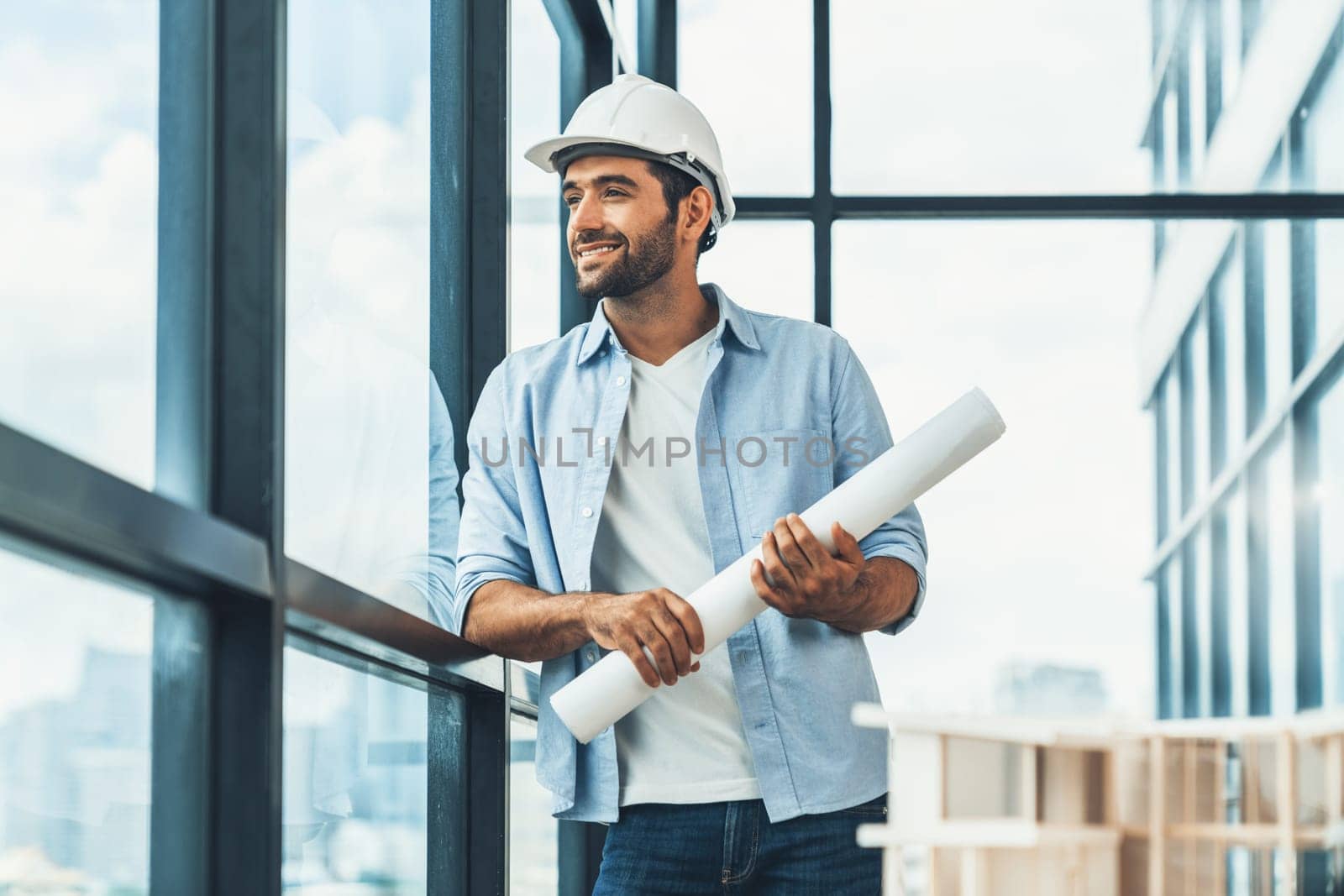 Smart civil engineer standing, walking while looking at house model and architectural equipment. Engineer with safety helmet standing near city view while standing near building model. Tracery.