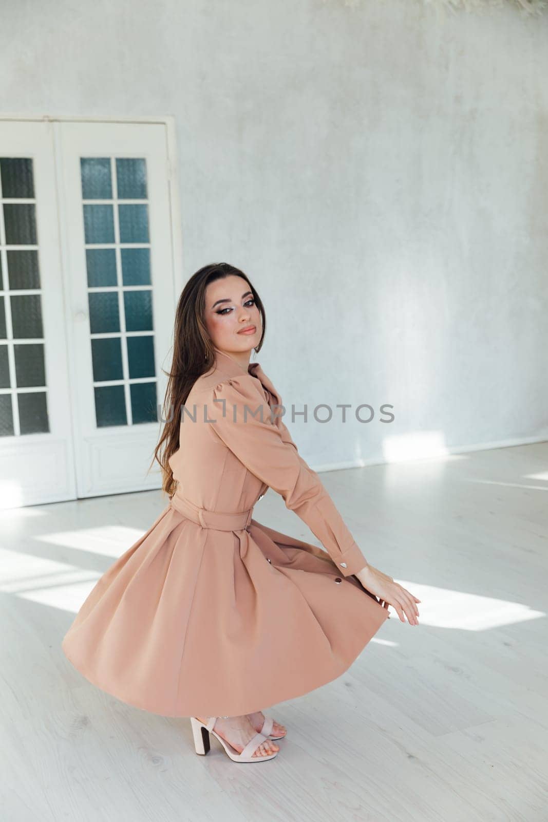 woman in dress posing in bright room near door