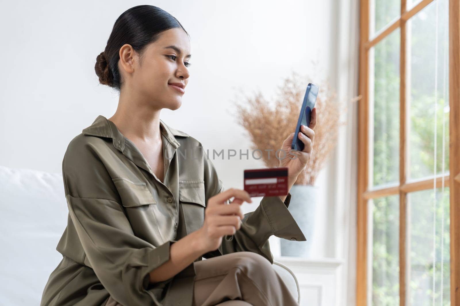 Young happy Asian woman buy product by online shopping at home while ordering items from the internet with credit card online payment protected by uttermost cyber security from online store platform