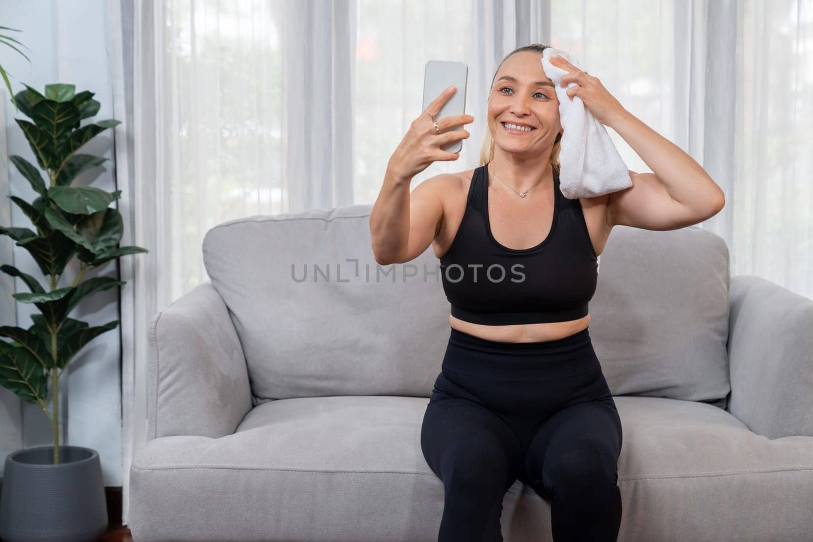 Active and sporty senior take selfie with smartphone after finishing home workout exercise. Healthy and fit body lifestyle for pensioner after retirement workout exercising at home. Clout