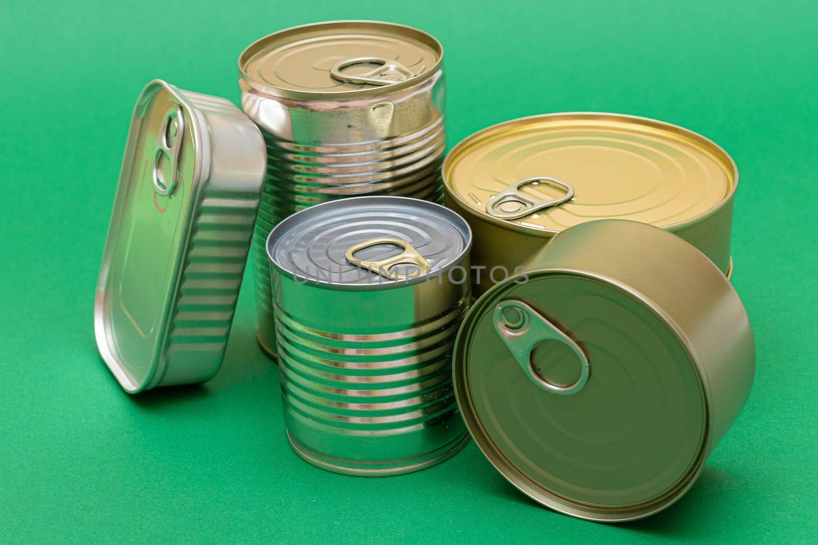 A Group of Stacked Tin Cans with Blank Edges on Green Background. Canned Food. Different Aluminum Cans for Safe and Long Term Storage of Food. Steel Sealed Food Storage Containers