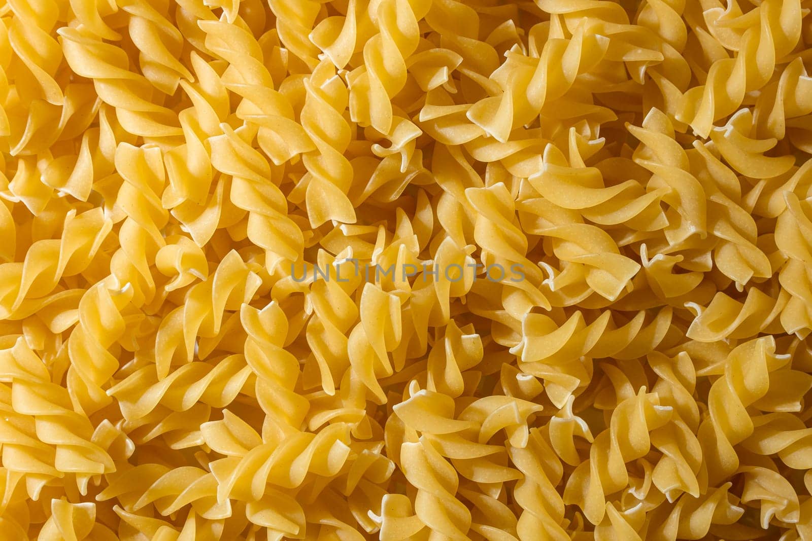 Uncooked Fusilli Pasta: A Culinary Canvas of Spiral Macaroni, Creating a Lively and Textured Background for Gourmet Cooking. Dry Pasta. Raw Macaroni - Top View, Flat Lay